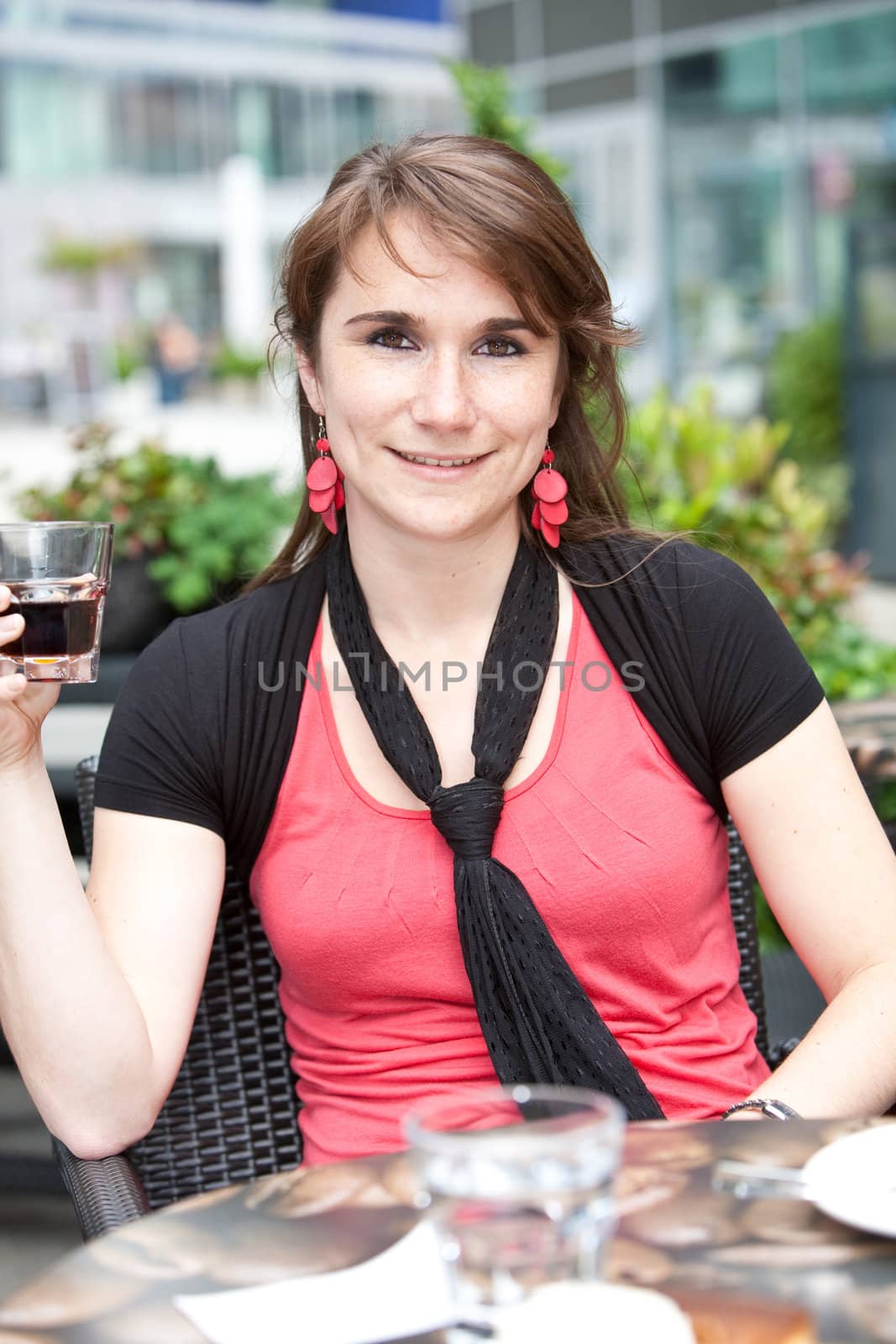 Pretty young girl sitting outdoors having a drink on a terrace