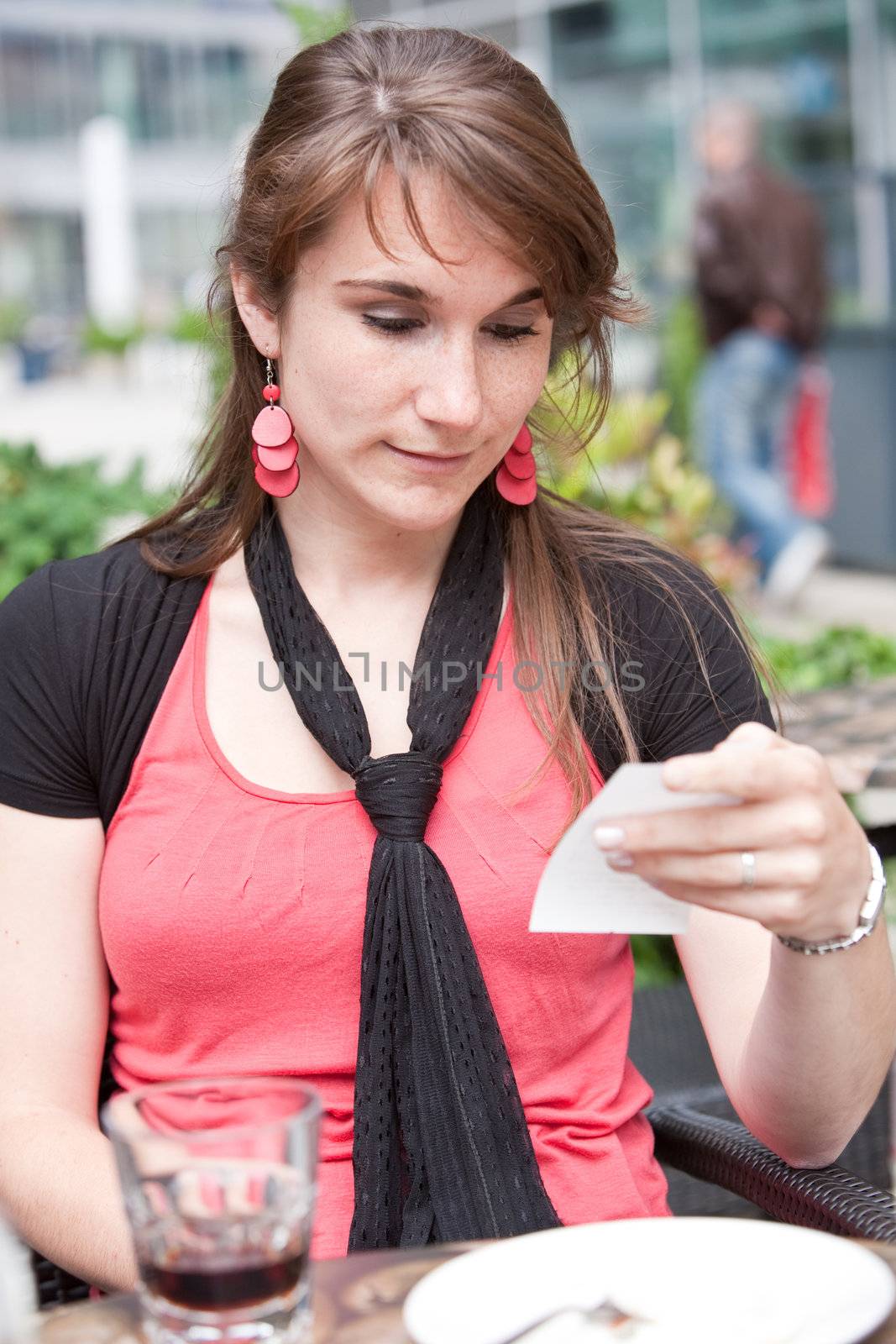 Pretty young girl checking the price of her purchases on  a terrace