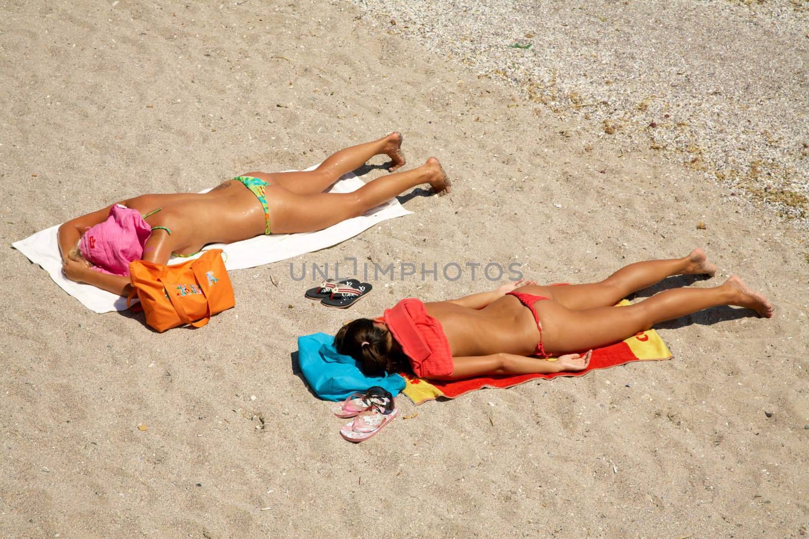 The girls taking sunbath on a beach sand