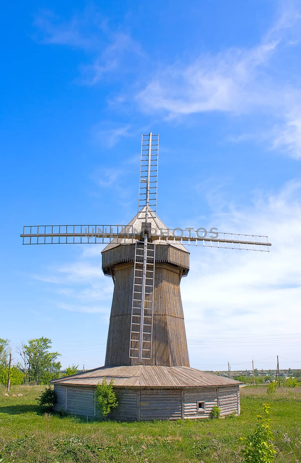 On  green grass, wooden windmill against  blue sky,Russia.