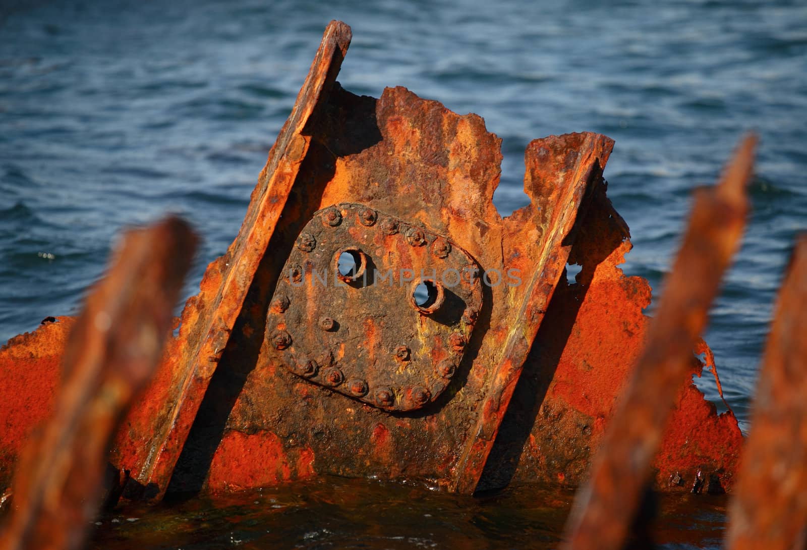 Rusty steel remains from an old ship uppear over the sea surface