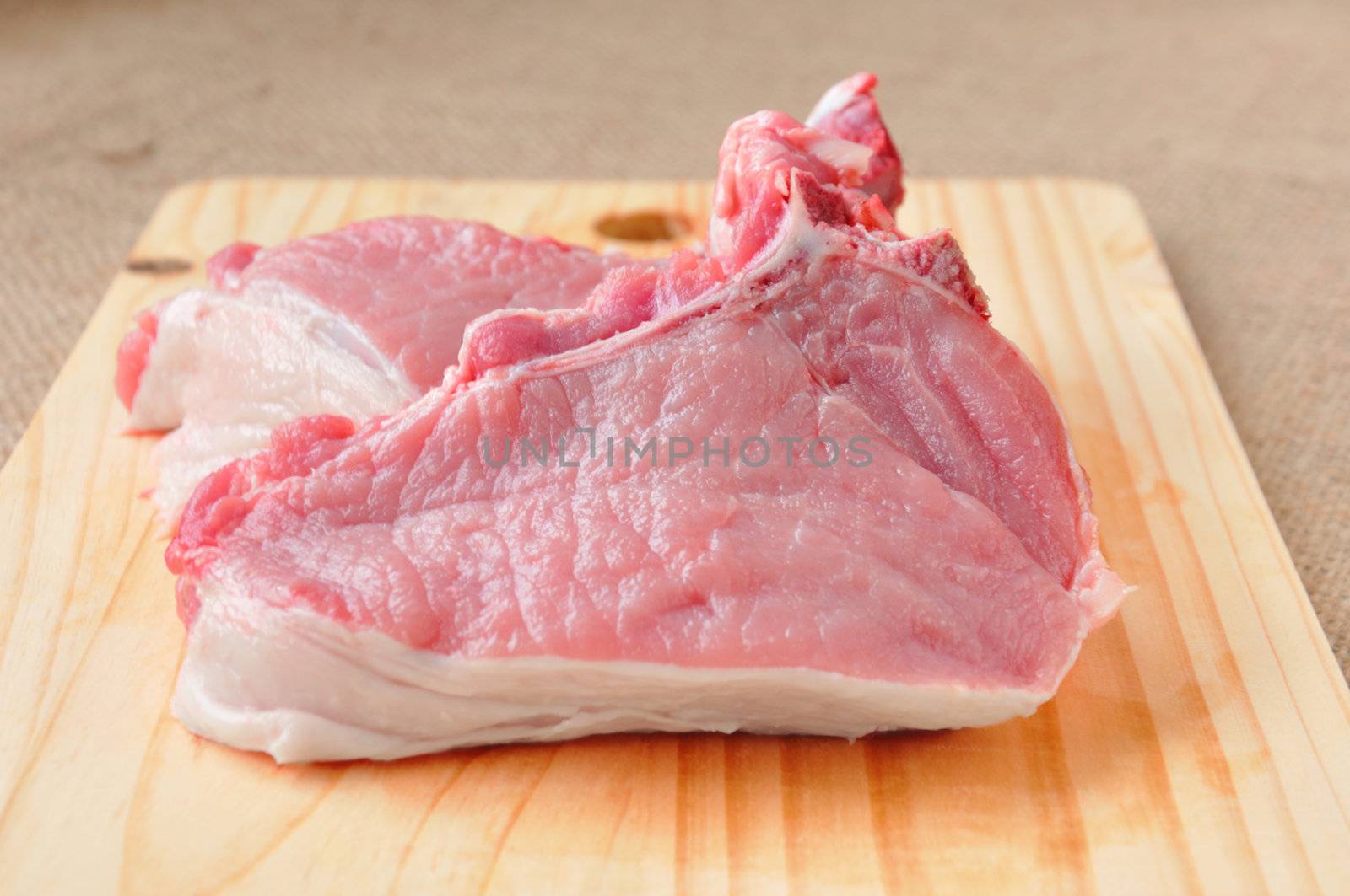 pieces of steak on the bone lying on a wooden board