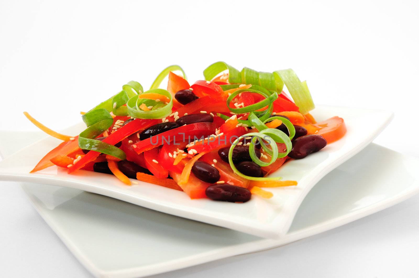 A salad of tomatoes, sweet peppers, red beans, carrots with sesame