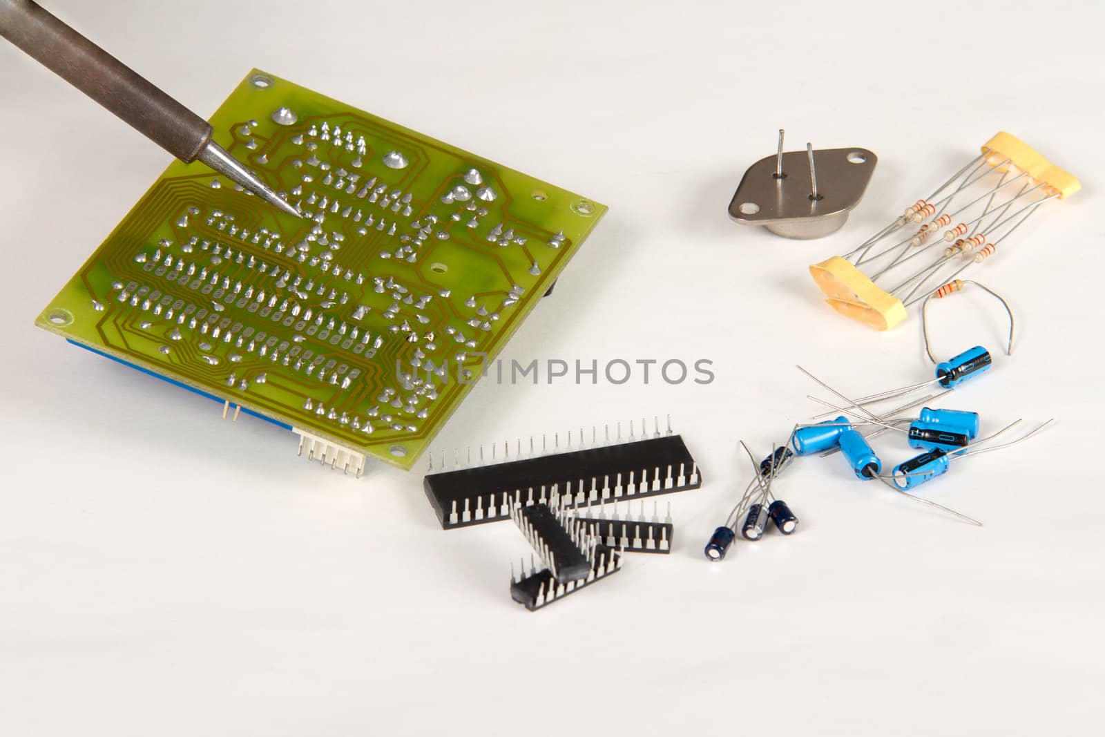 Engineer soldering circuit board surrounded by spare components