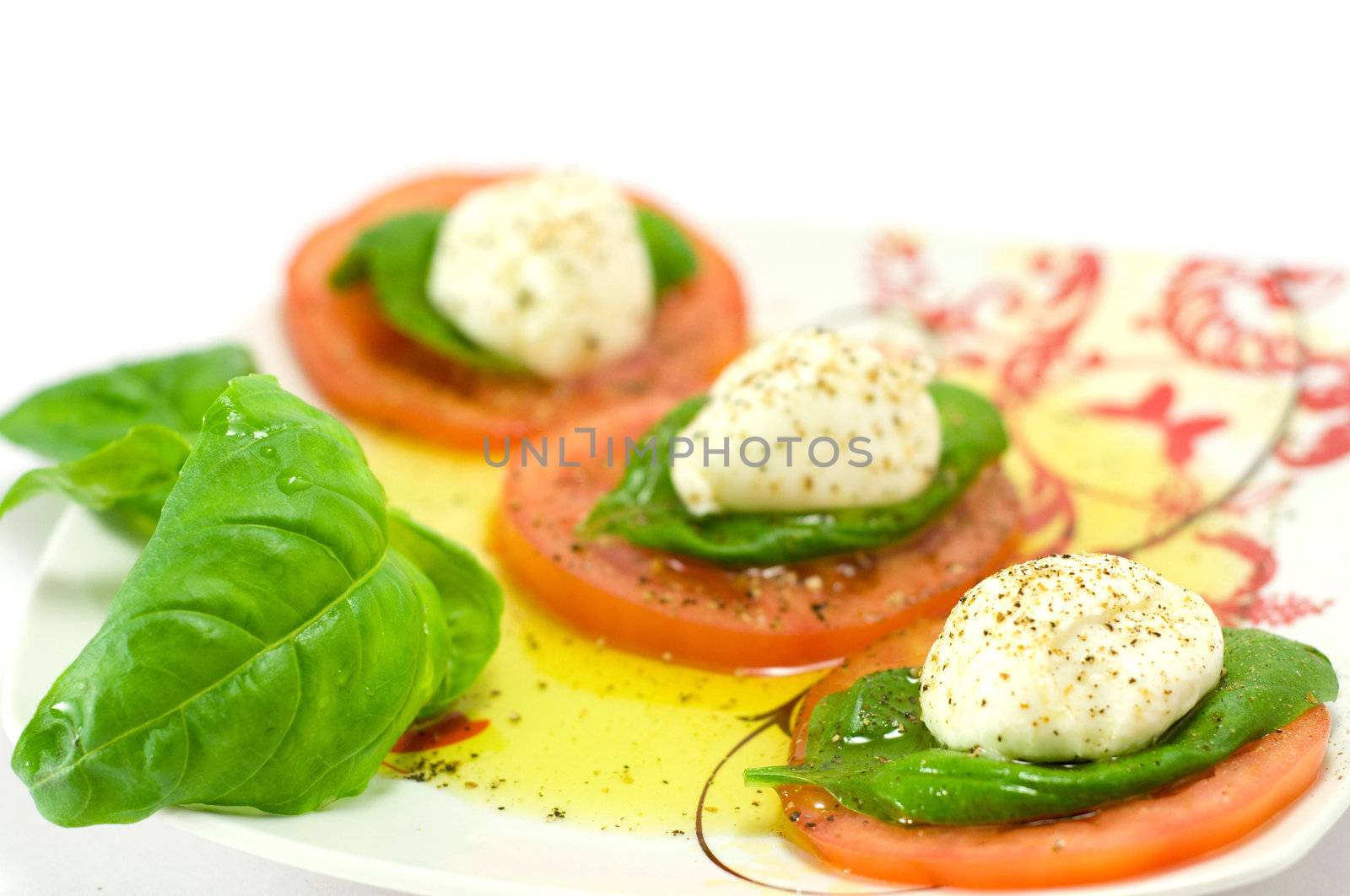 Caprese salad close-up with olive oil green basil and  pepper 