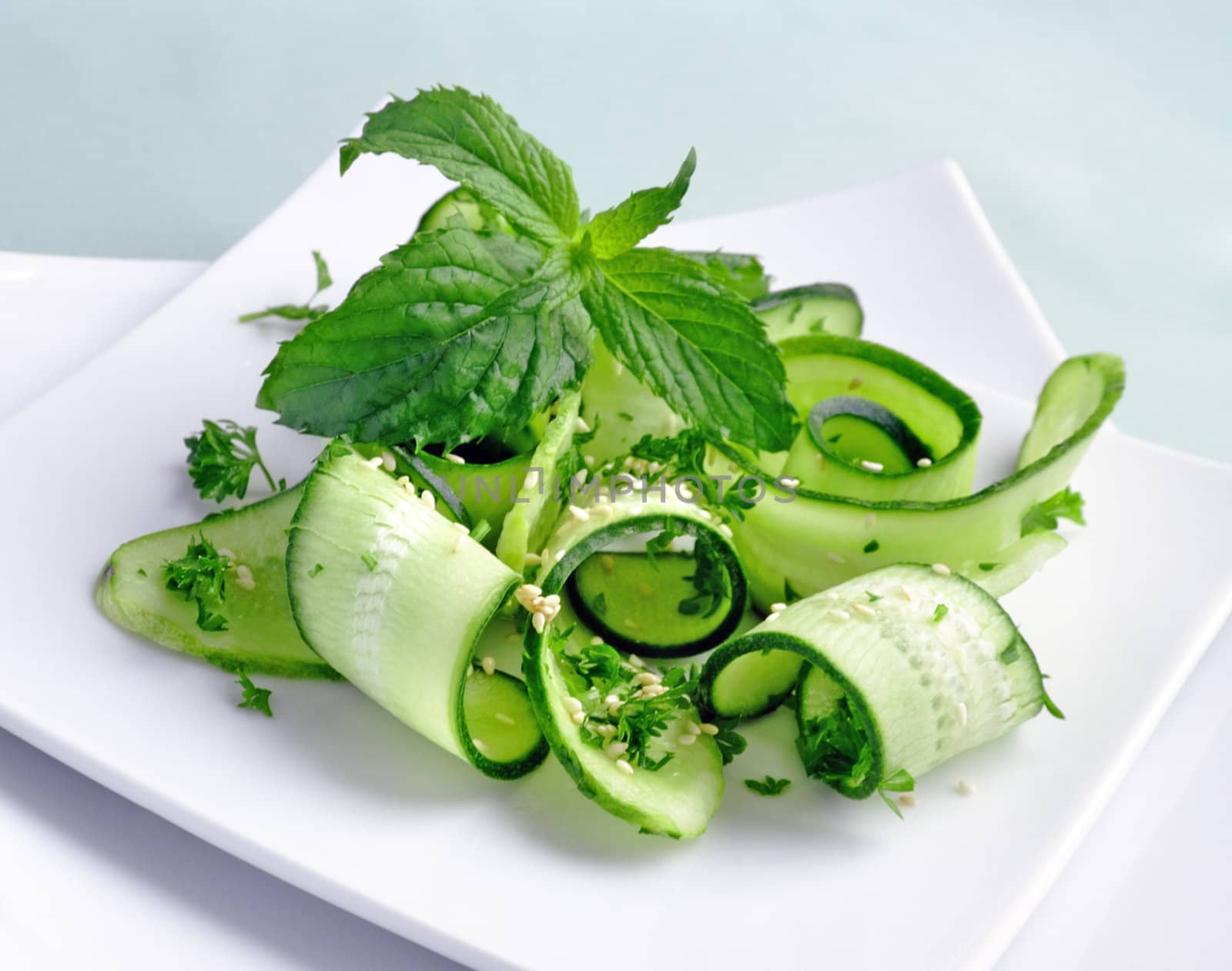 Salad of sliced green cucumbers with herbs and sesame seeds with mint leaves