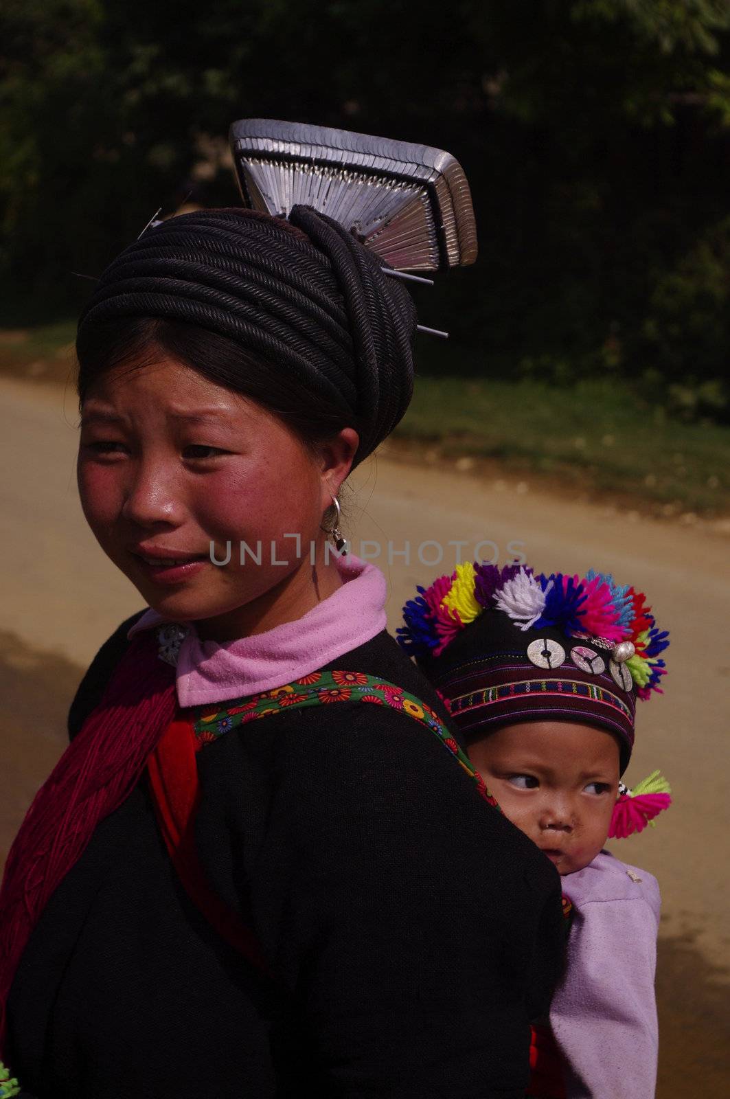 Young woman black Dao,with her baby on the raod to Lai Chau coming to market.She wears the hat typical of black Dao “ Tien”. Her baby has very nice hat covered with multicolored pompons