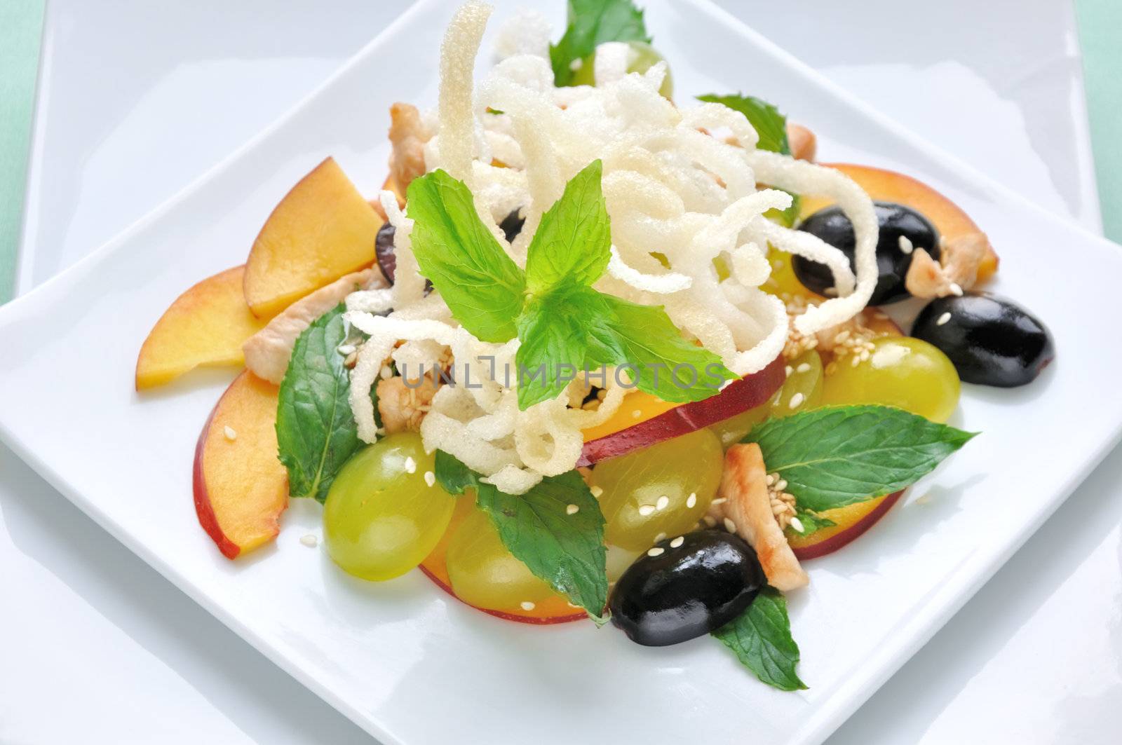 light salad with chicken, grapes, nectarines, sesame, with lemon dressing, decorated with fried rice noodles with mint