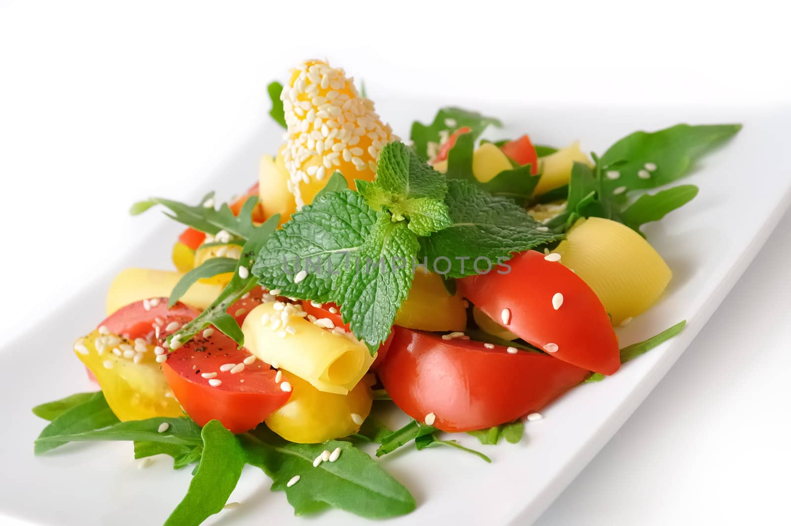 Salad of red and yellow tomato with cheese, arugula, sesame