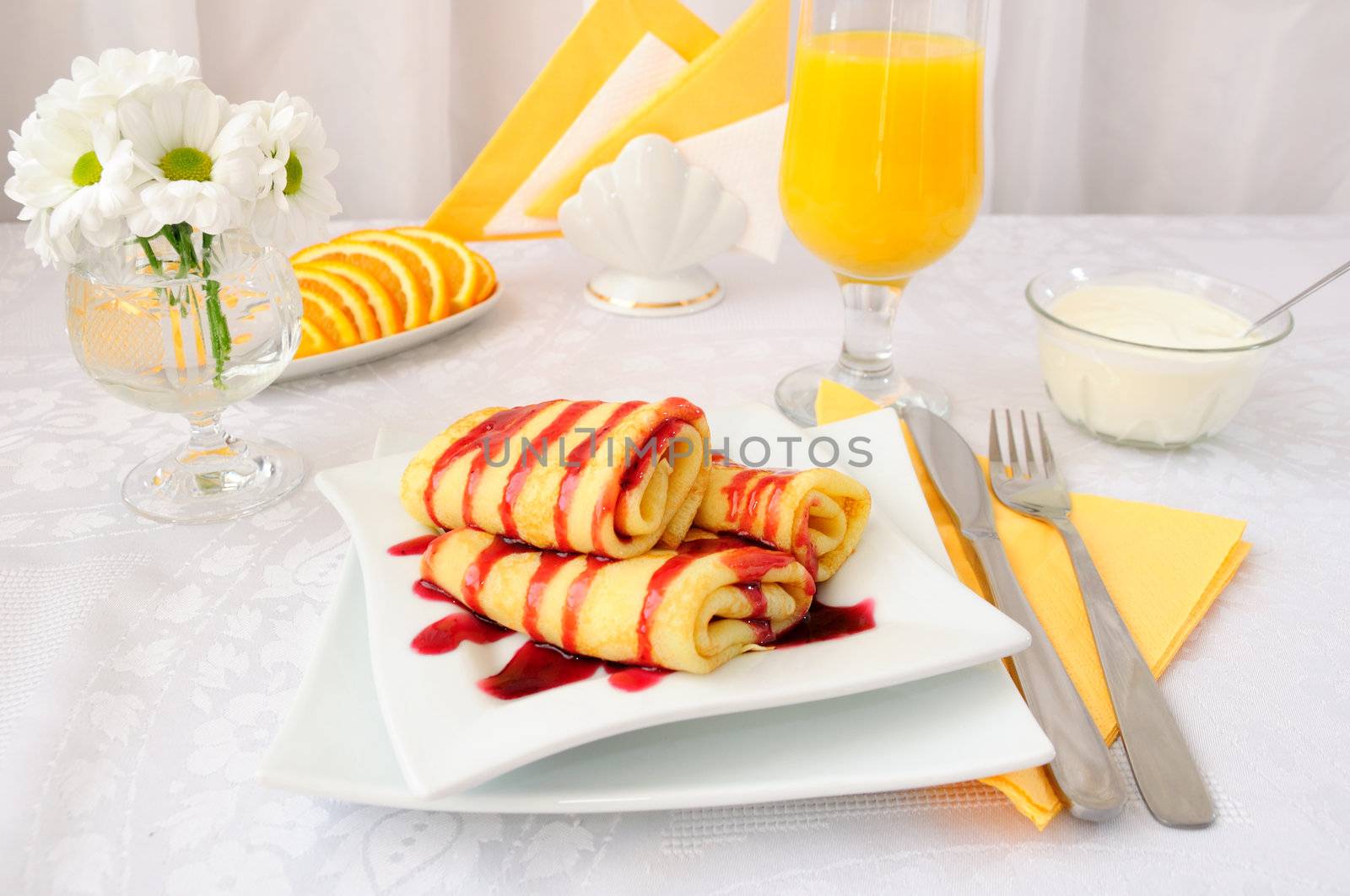 Breakfast with pancakes poured cherry syrup and orange juice
