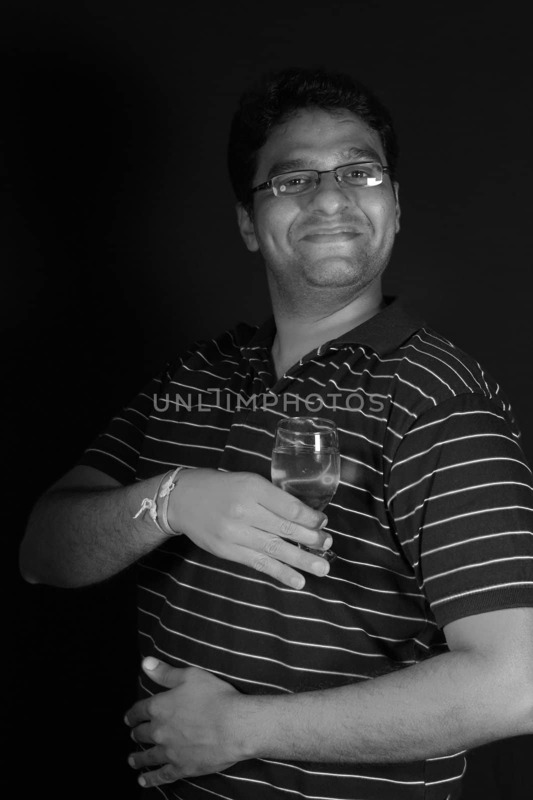 A portrait of a funny Indian actor holding a wineglass.