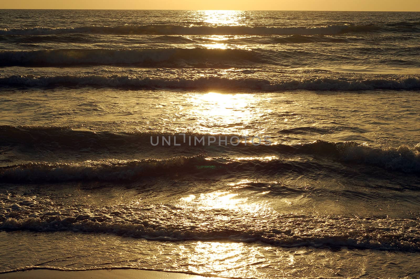 Sand and water sea wave at the sunset