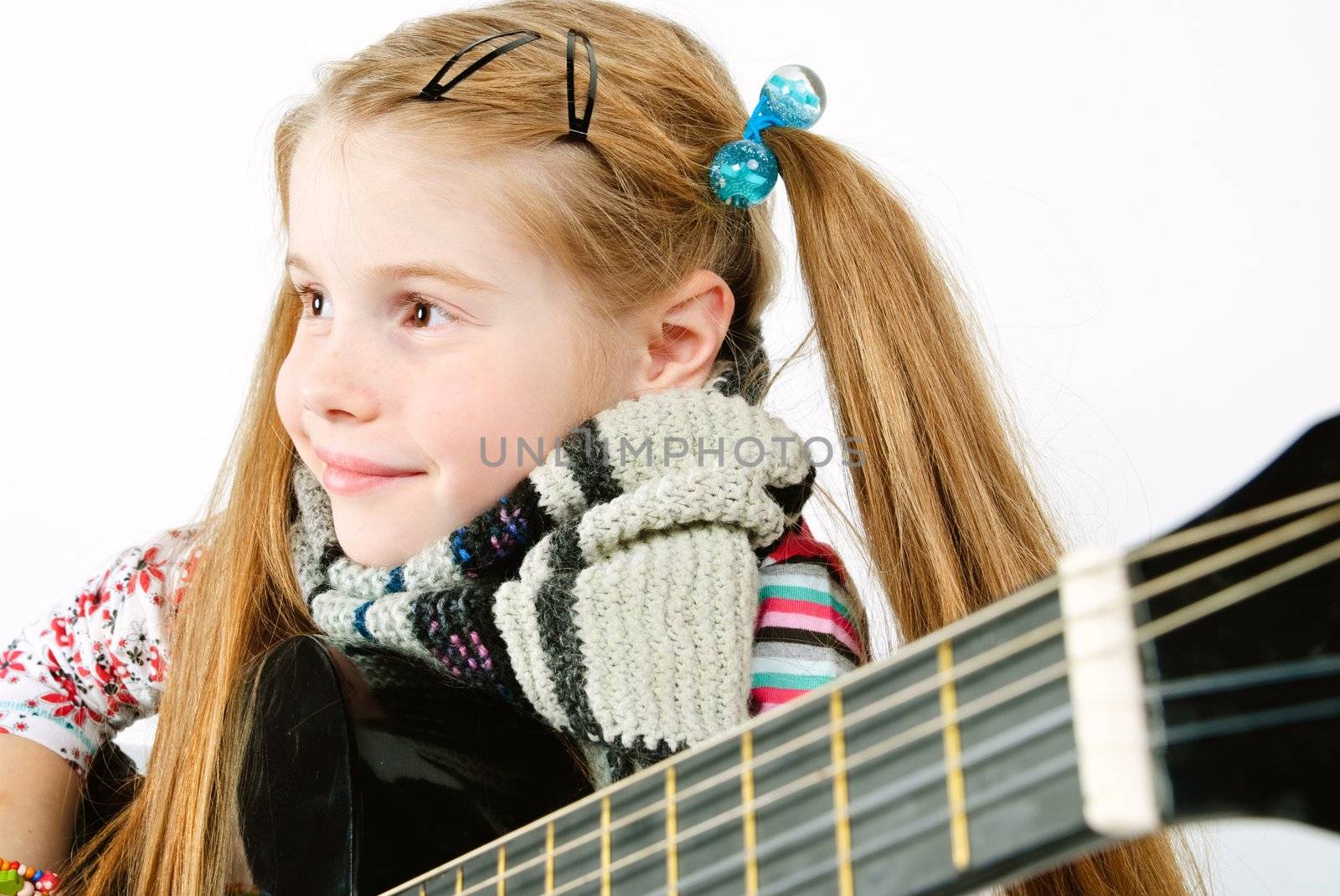 studio shot of pretty little girl playing black acoustic guitar