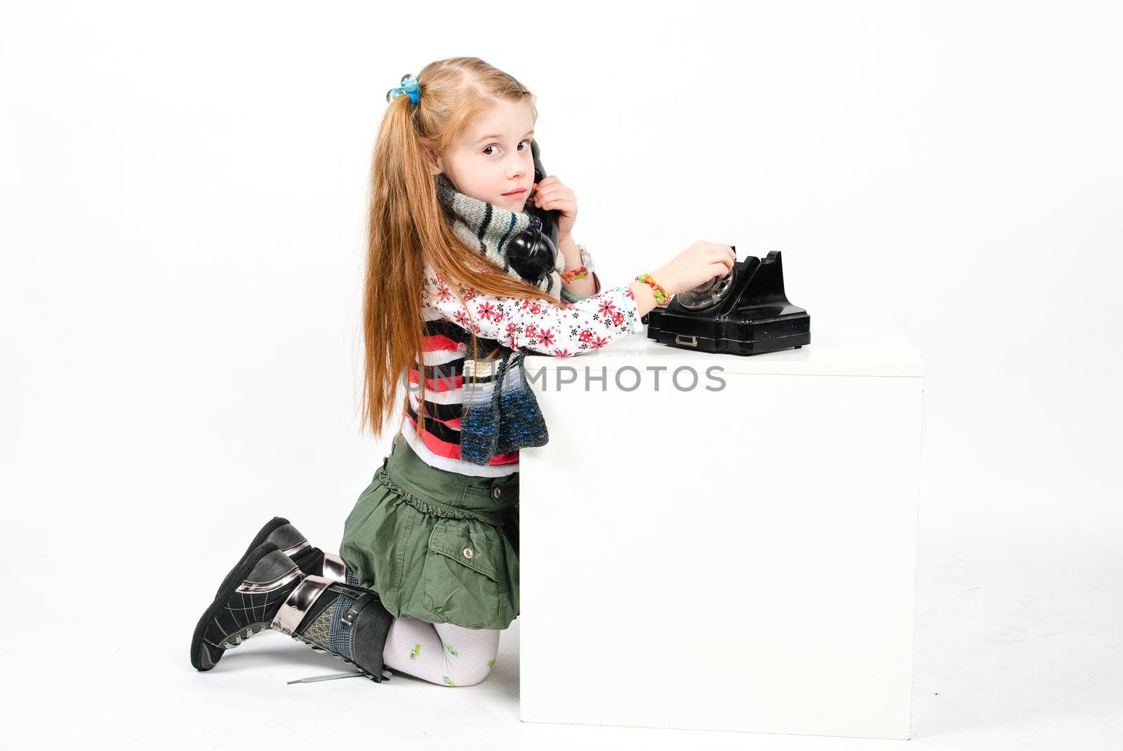 studio shot of pretty little girl calling the old phone
