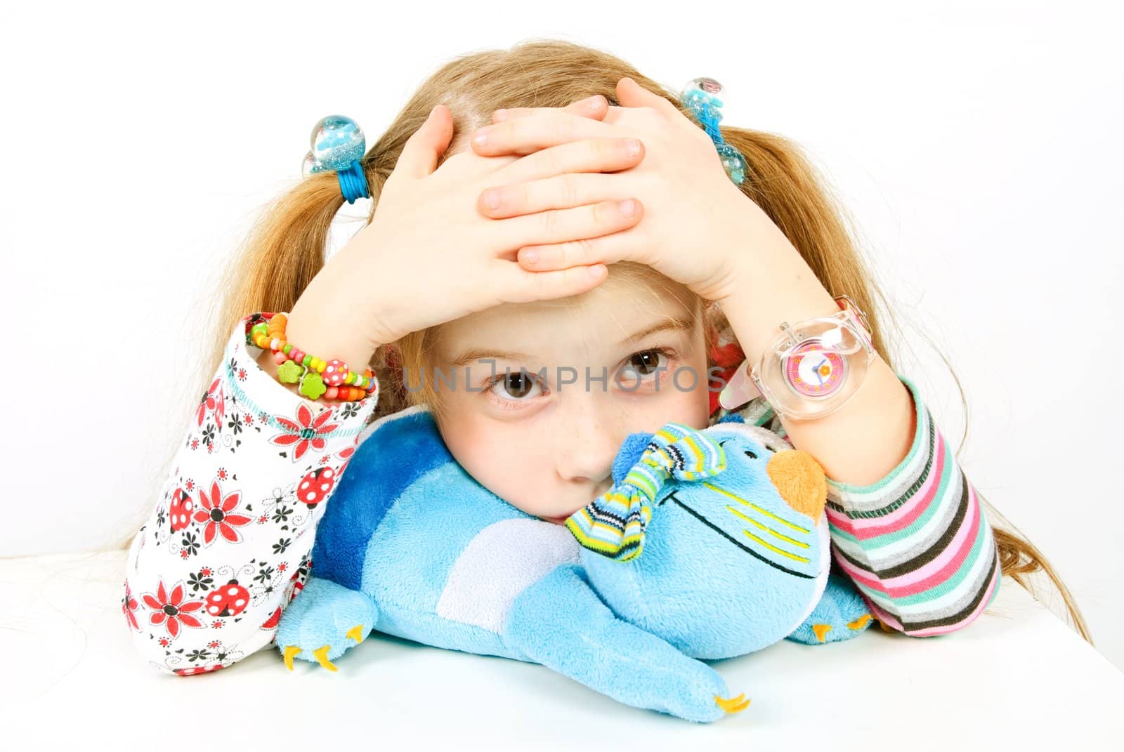 studio shot of sad pretty little girl with blue cat toy