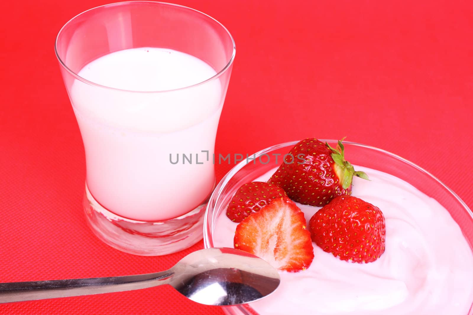 Shot of glass of milk, fruit yogurt and strawberries on red background