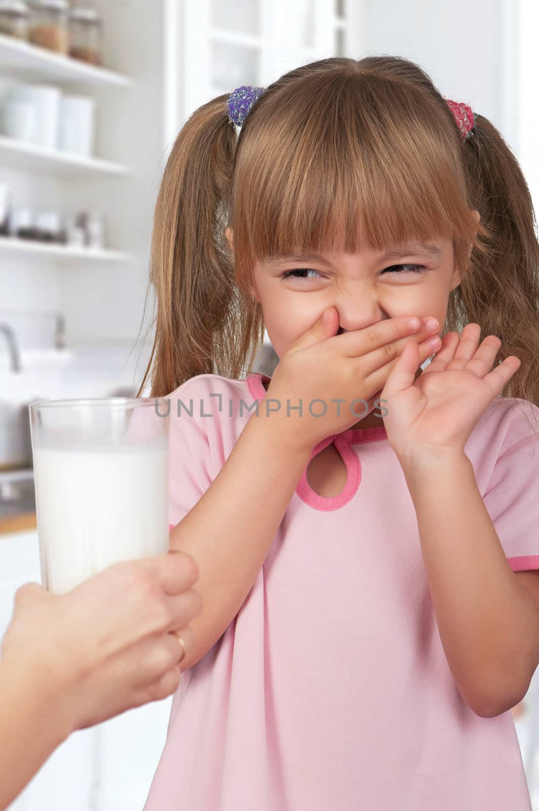 Cute little girl and glass of milk in kitchen