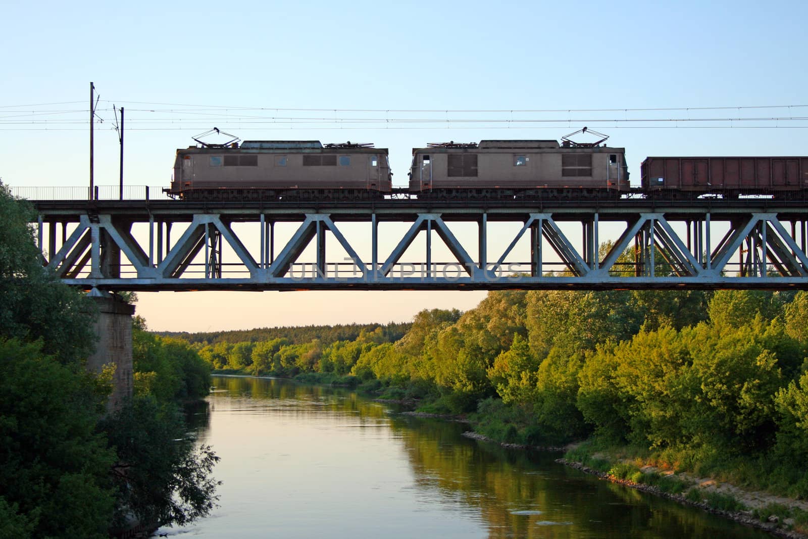 Freight train passing the steel bridge over the river