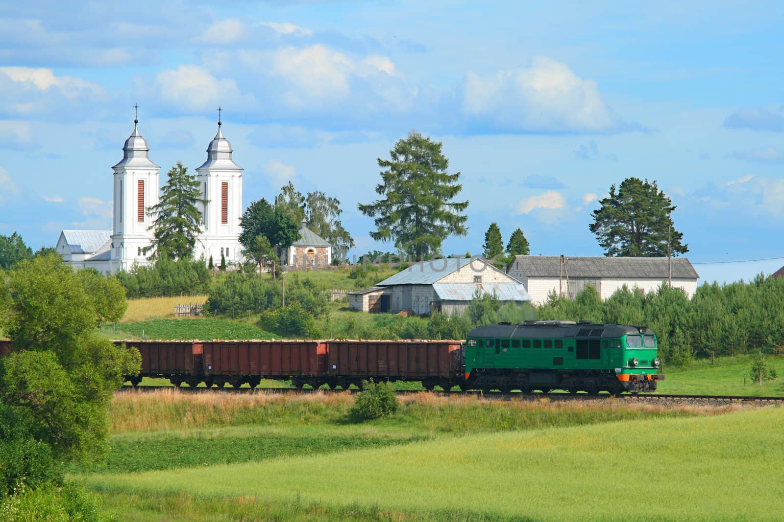 Freight train passing the village with a church in background
