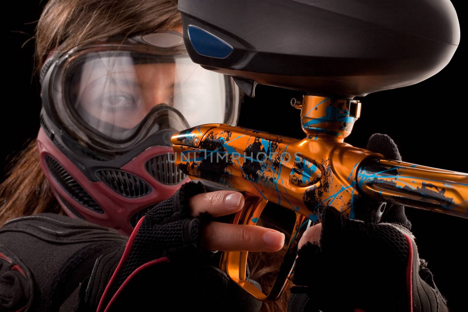 Image of a paintball player in protective helmet aiming the target