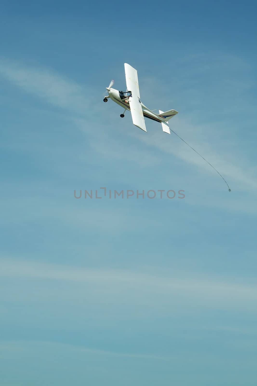 small white aeroplane flying, there's a hook on his tail which is used to carry a advertisement or so