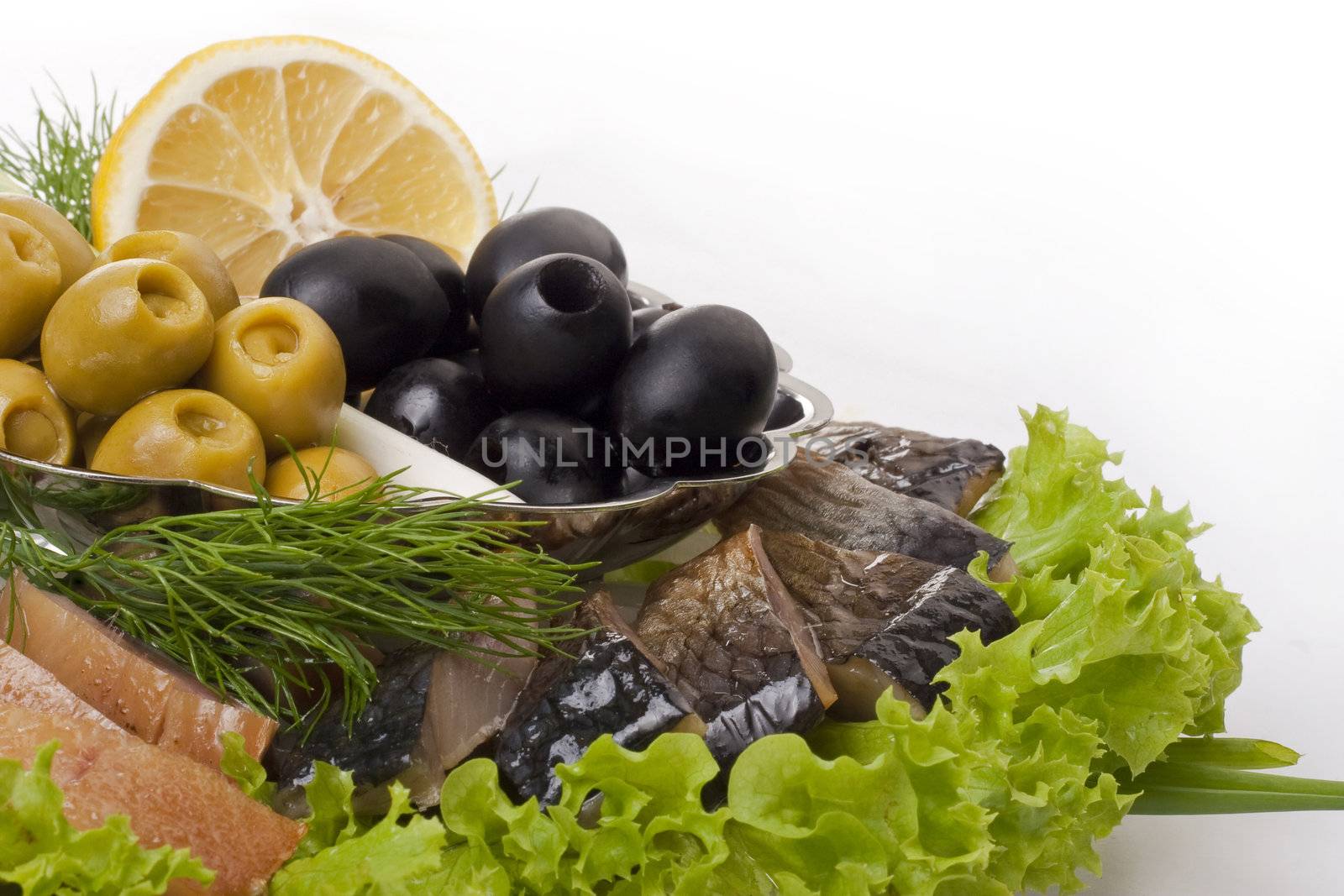 A composition with herring pieces and vegetables isolated on white. Closeup