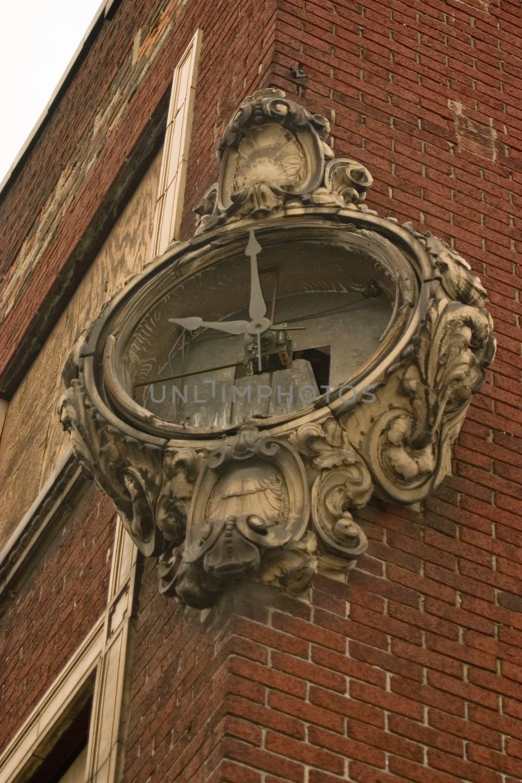 This is a picture of a broken clock on an old dilapidated brick building in a rundown intercity neighborhood.