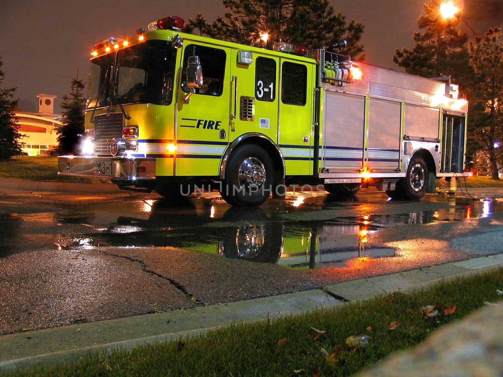 This is a fire engine, pumper truck that was hooked to a hydrant and spraying water during the evening hours.