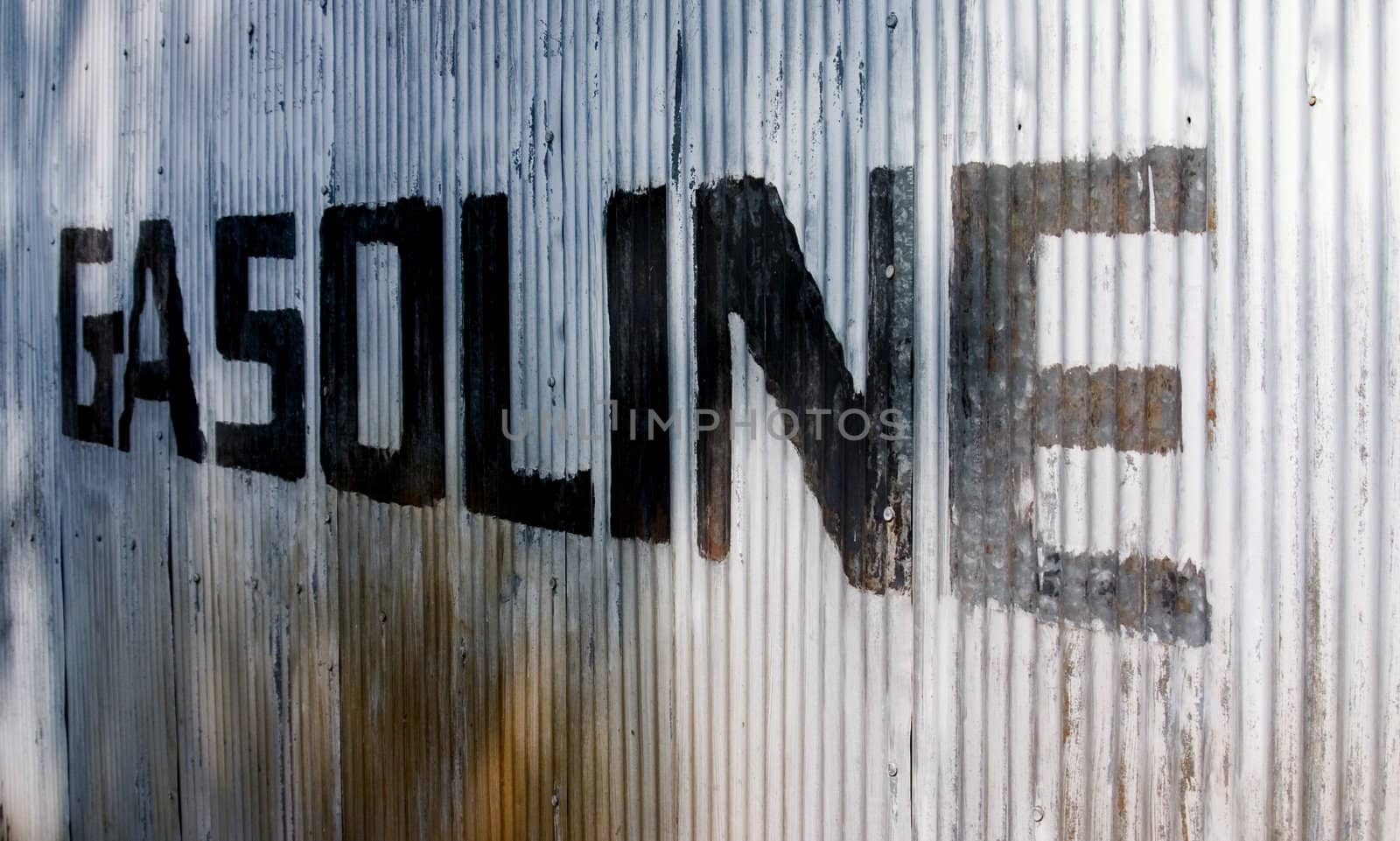 This is a picture of an old sign hand painted on a corrugated steel wall from an old abandoned gas station.