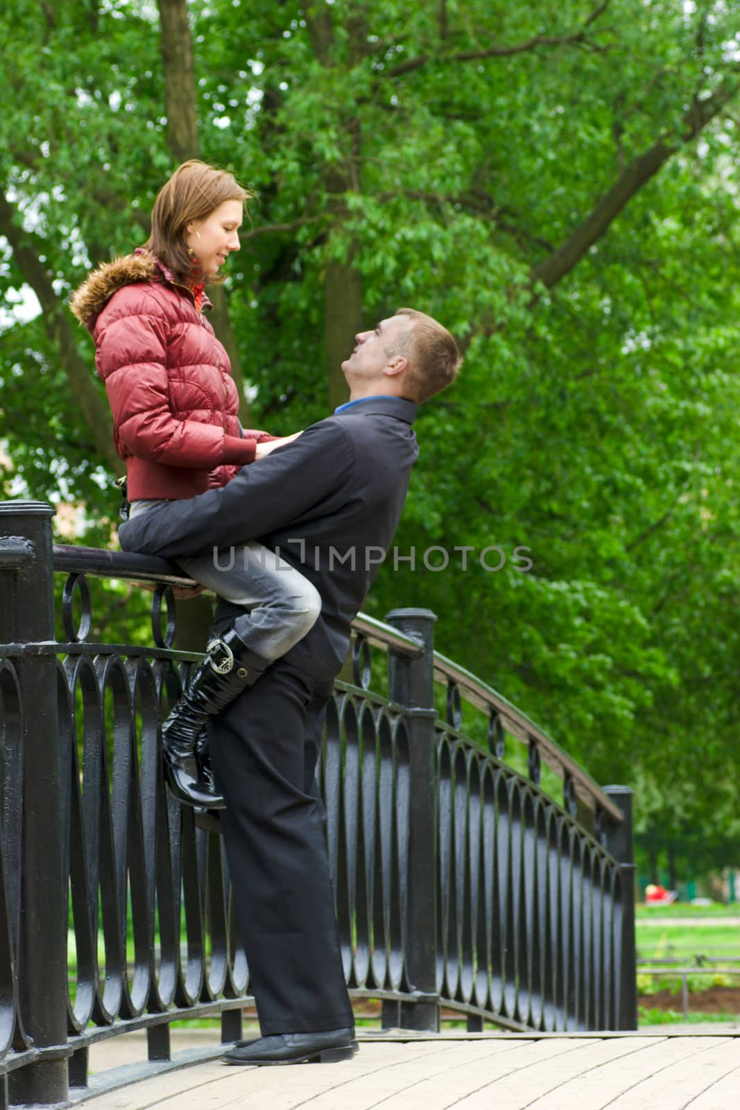 Happy young loving couple bridge in park