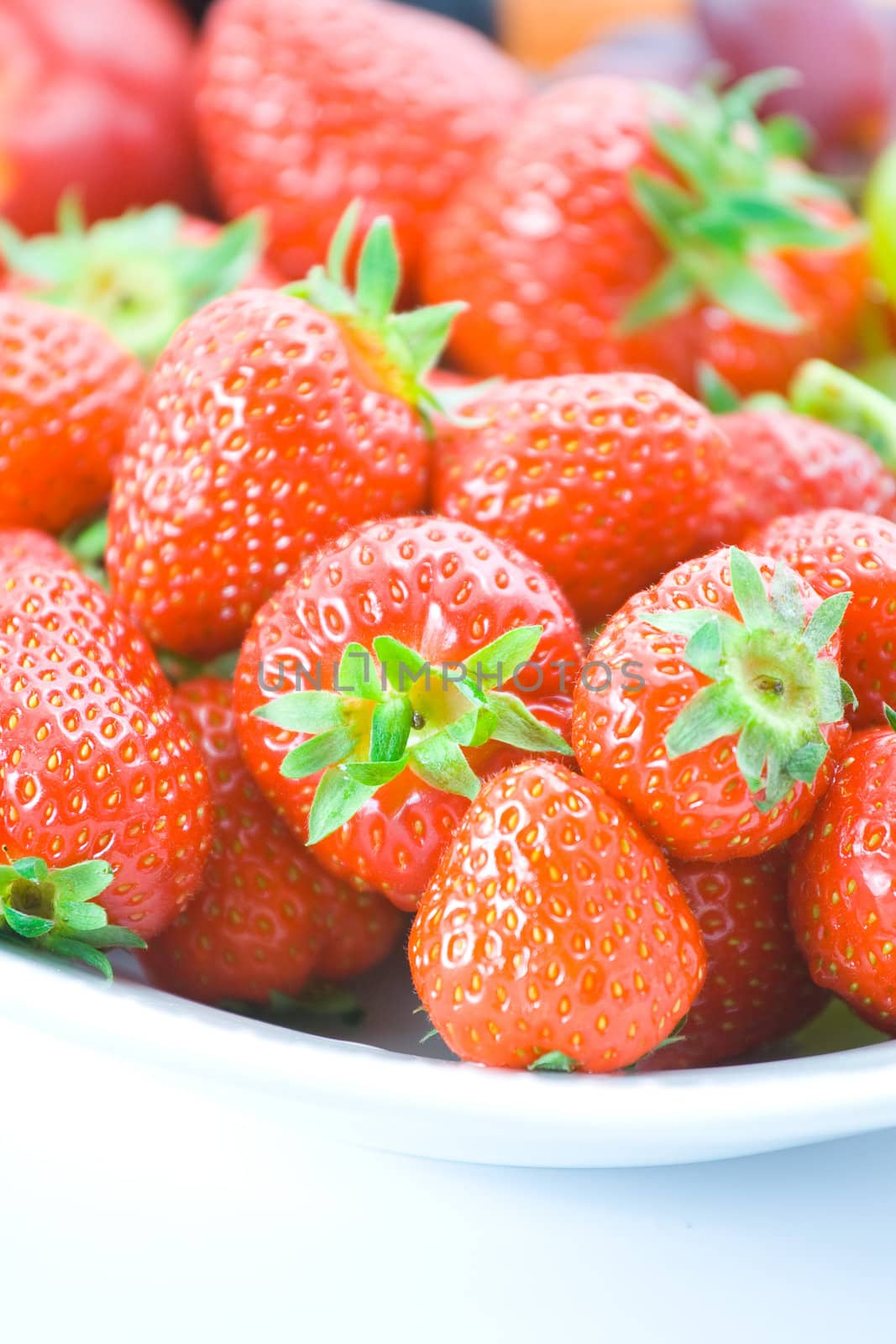 Delicious red strawberries on white plate with shallow depth of field.