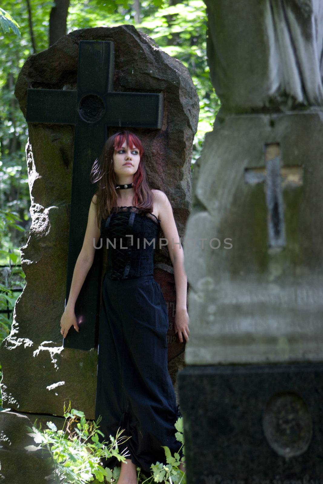 Gothic girl walking through cemetery looking away