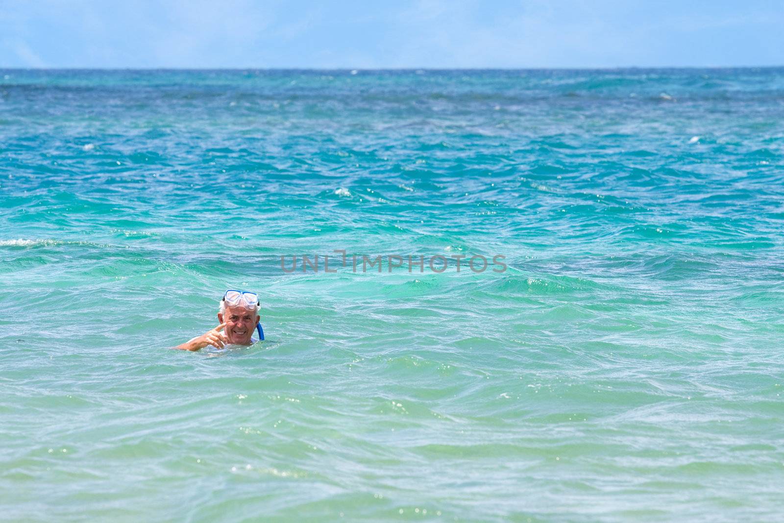 An older elderly man snorkels in tropical waters in the Caribbean off of the Puerto Rican island of Culebra.