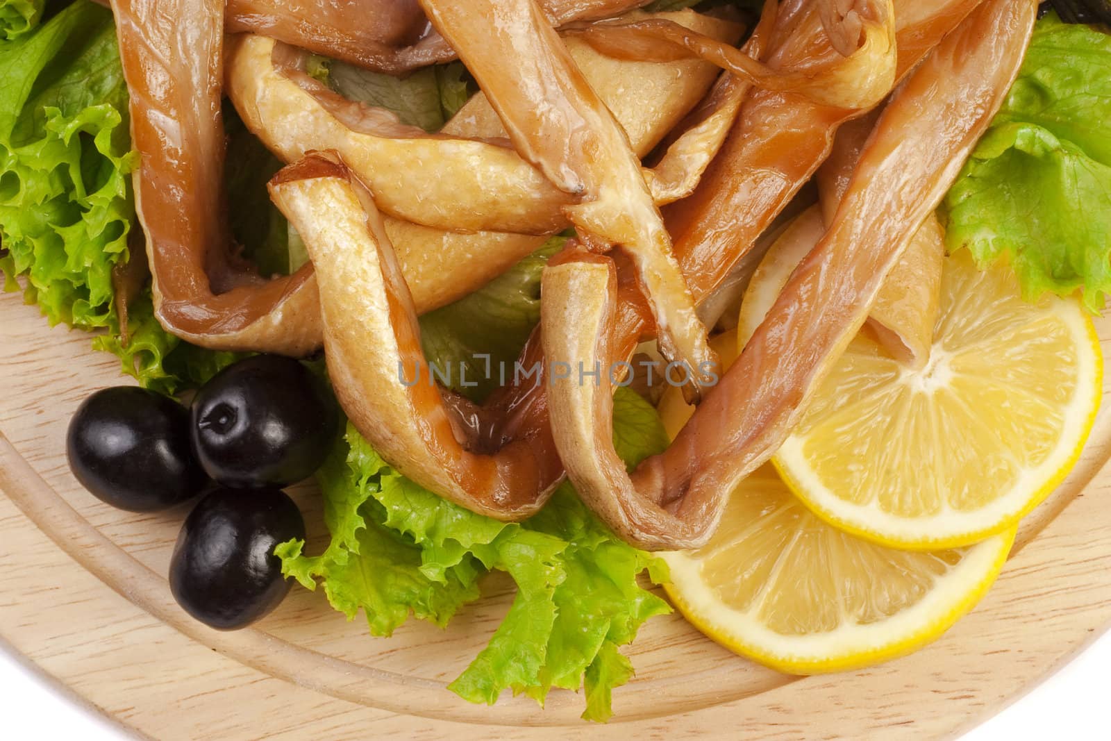 A composition with smoked salmon bellies on wooden plate isolated on white. Top view Closeup.