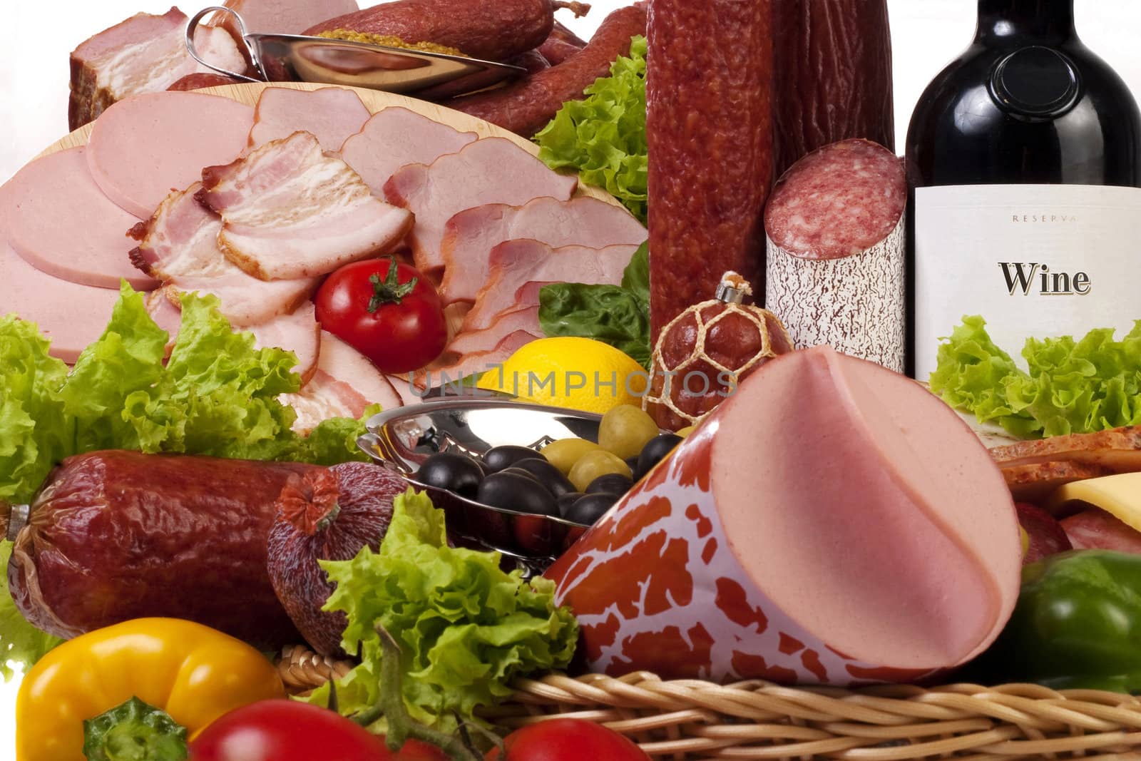 A composition of meat and vegetables with a bottle of wine isolated on white
