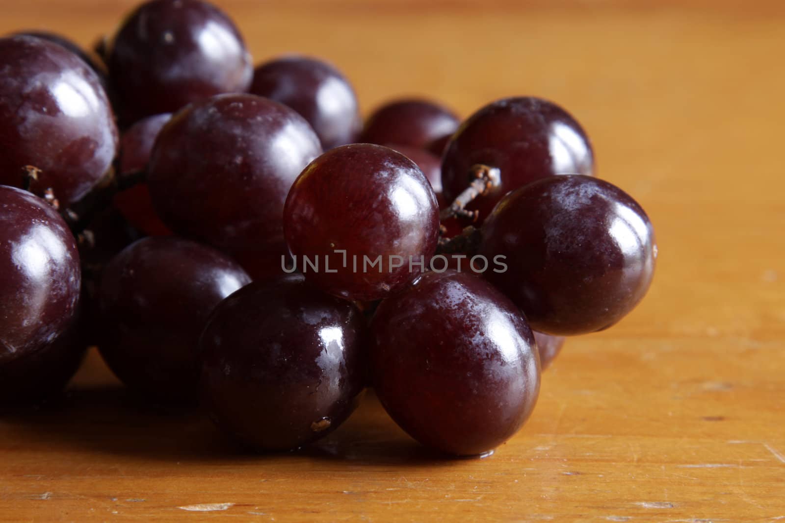 A cluster of juicy red grapes on a wood table.
