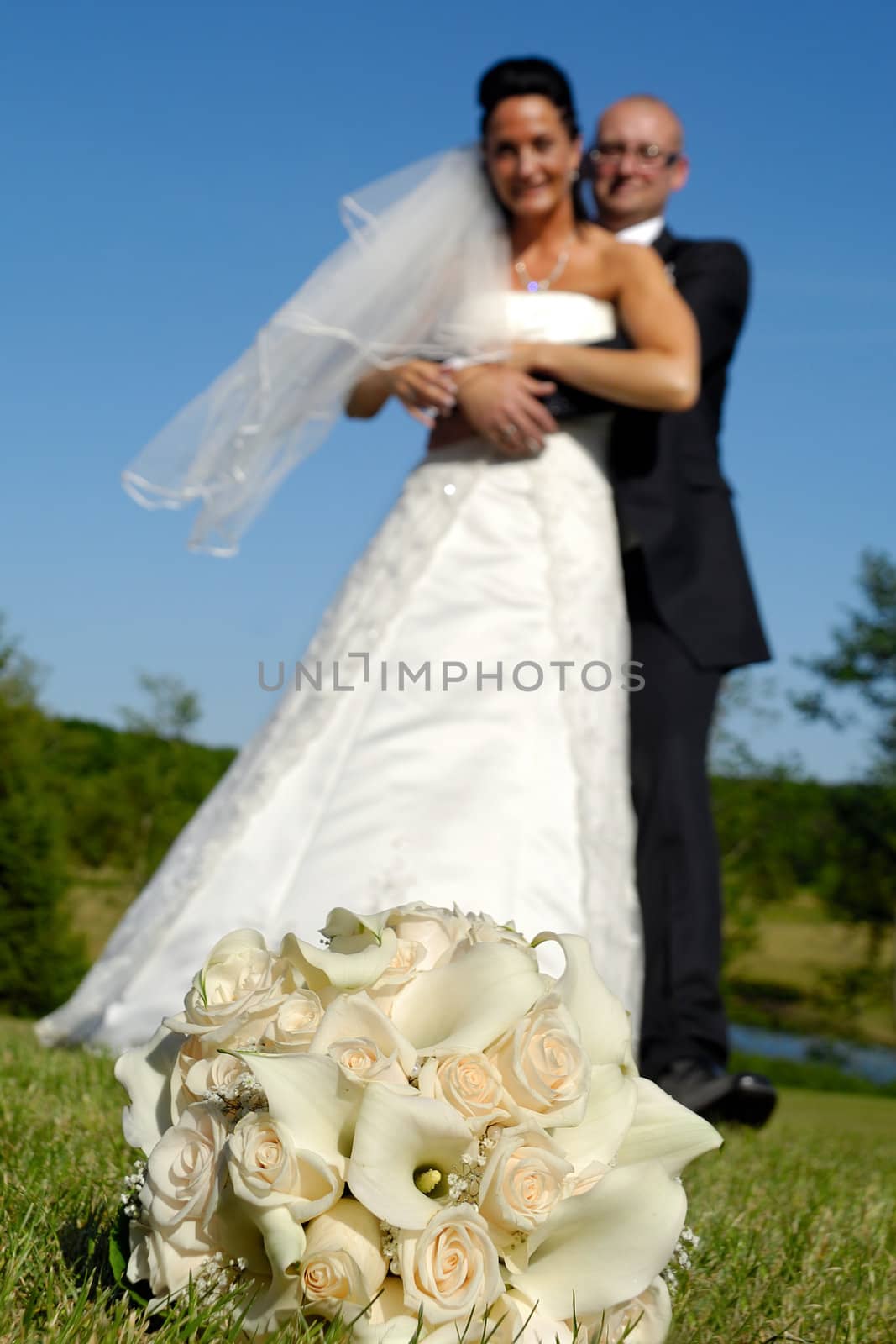 Wedding bouquet in focus and couple in blur