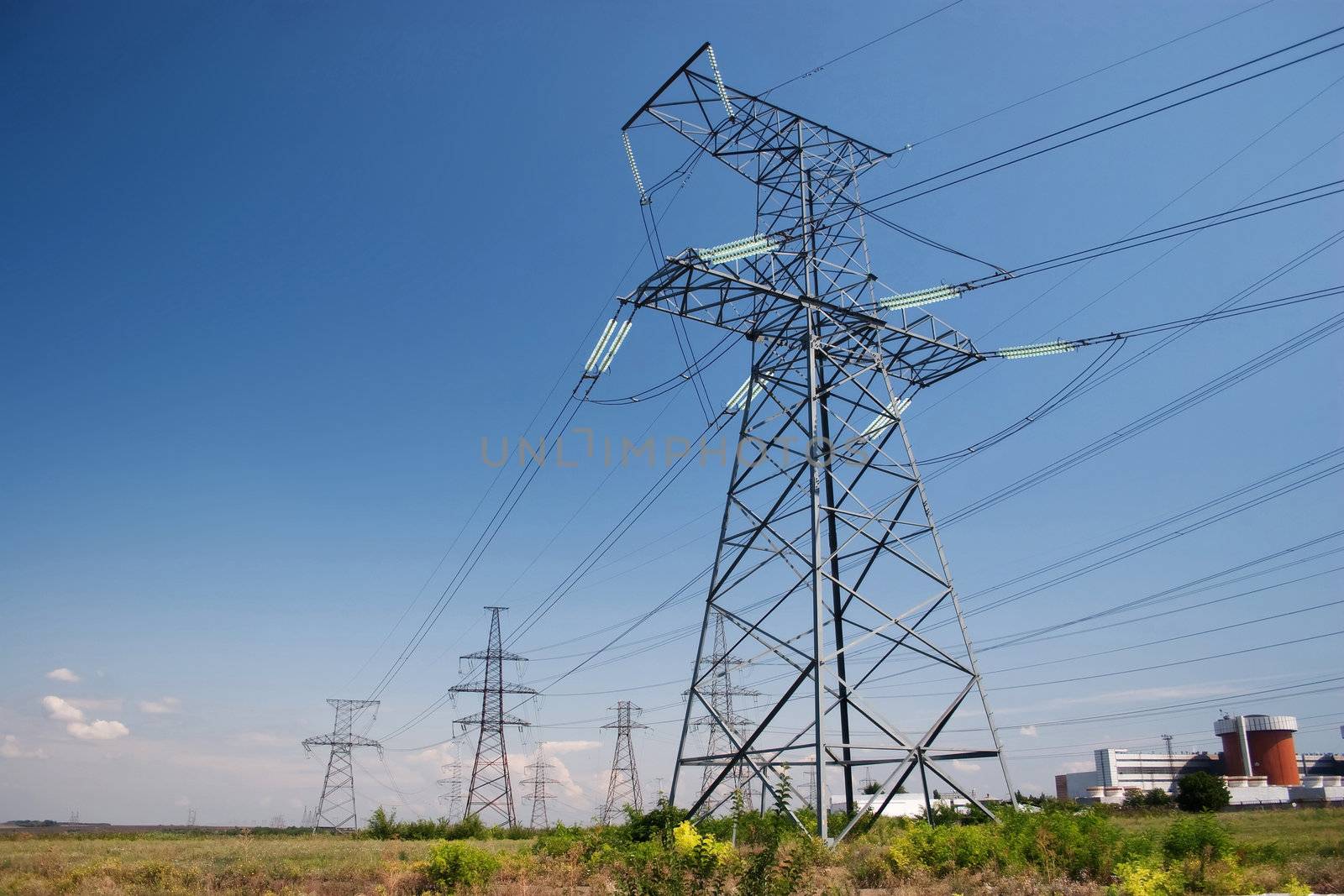 Electrical power lines and nuclear power station under clear blue sky