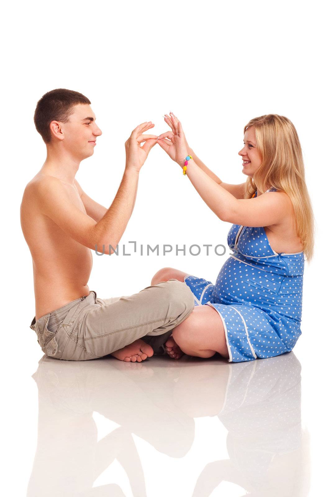 Pregnant woman with her husband kissing by hands. Studio shoot on white.
