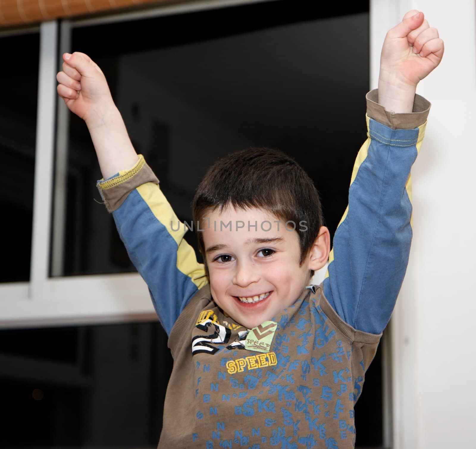 Cute little boy rises his arms in a V-sign