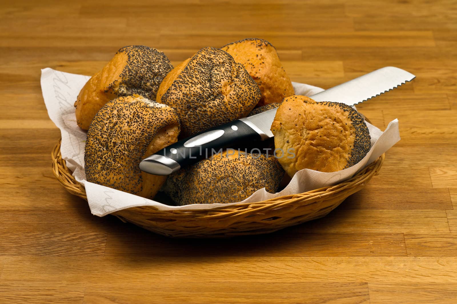 Fresh Bread Rolls and knife  In Basket on wooden table