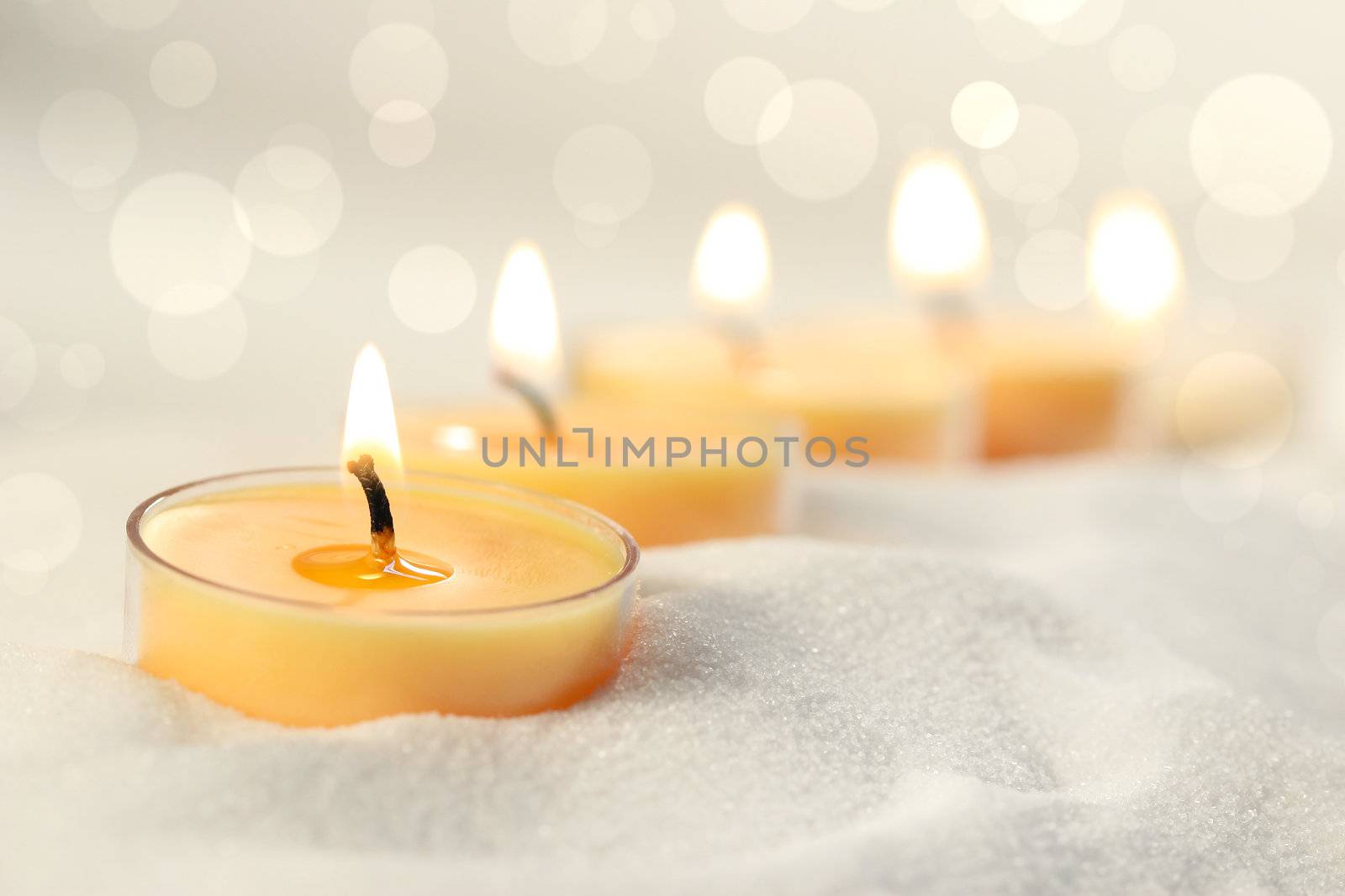 Votive candles in sand lit and arranged for ambiance