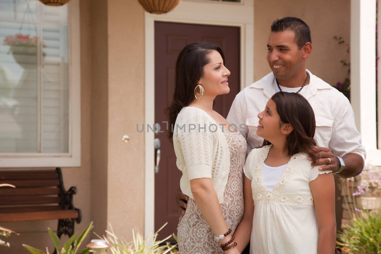 Small Hispanic Mother, Father and Daughter in Front of Their Home.