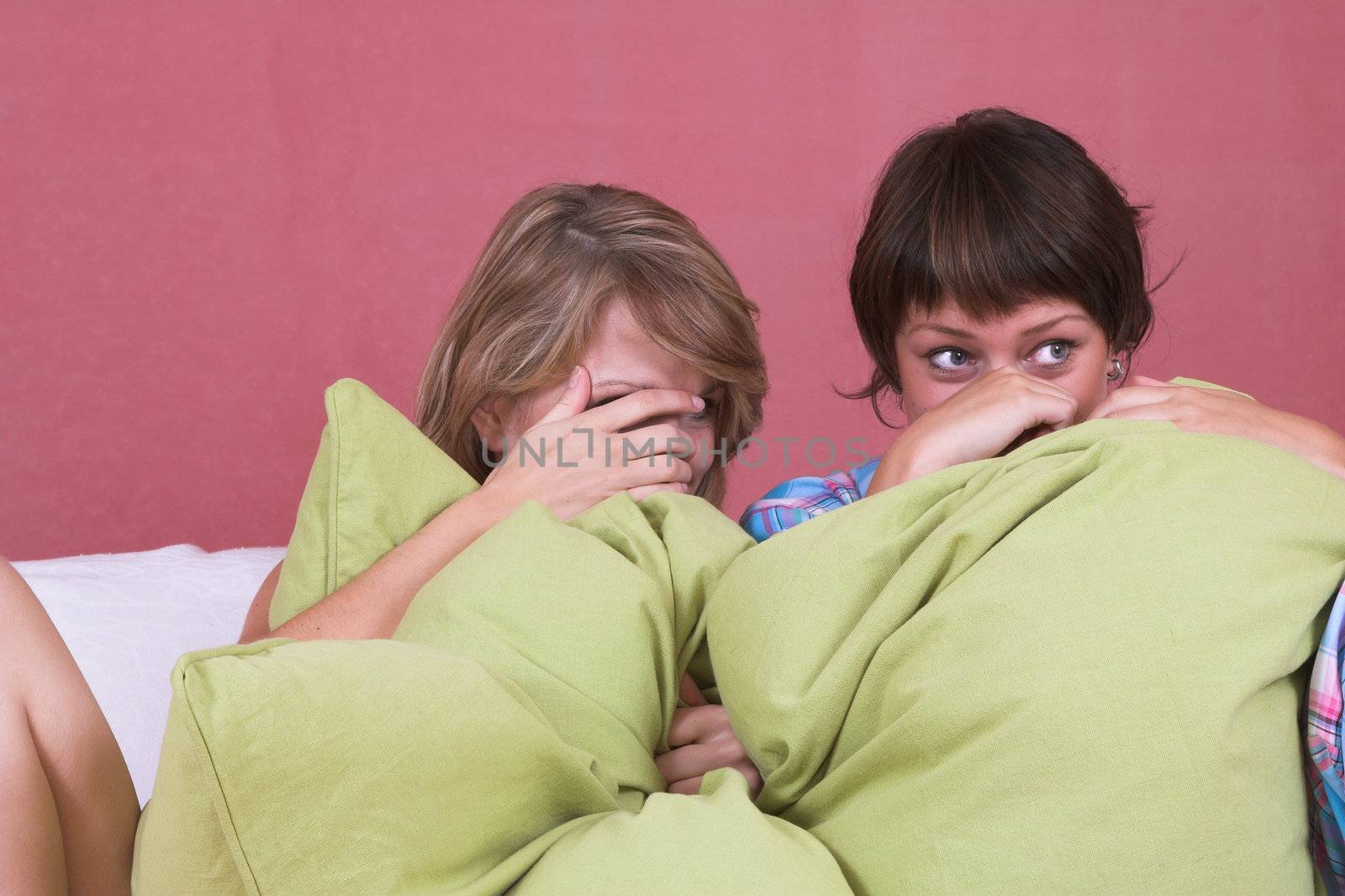 Two girls watching a scary movie together, hiding behind their hands