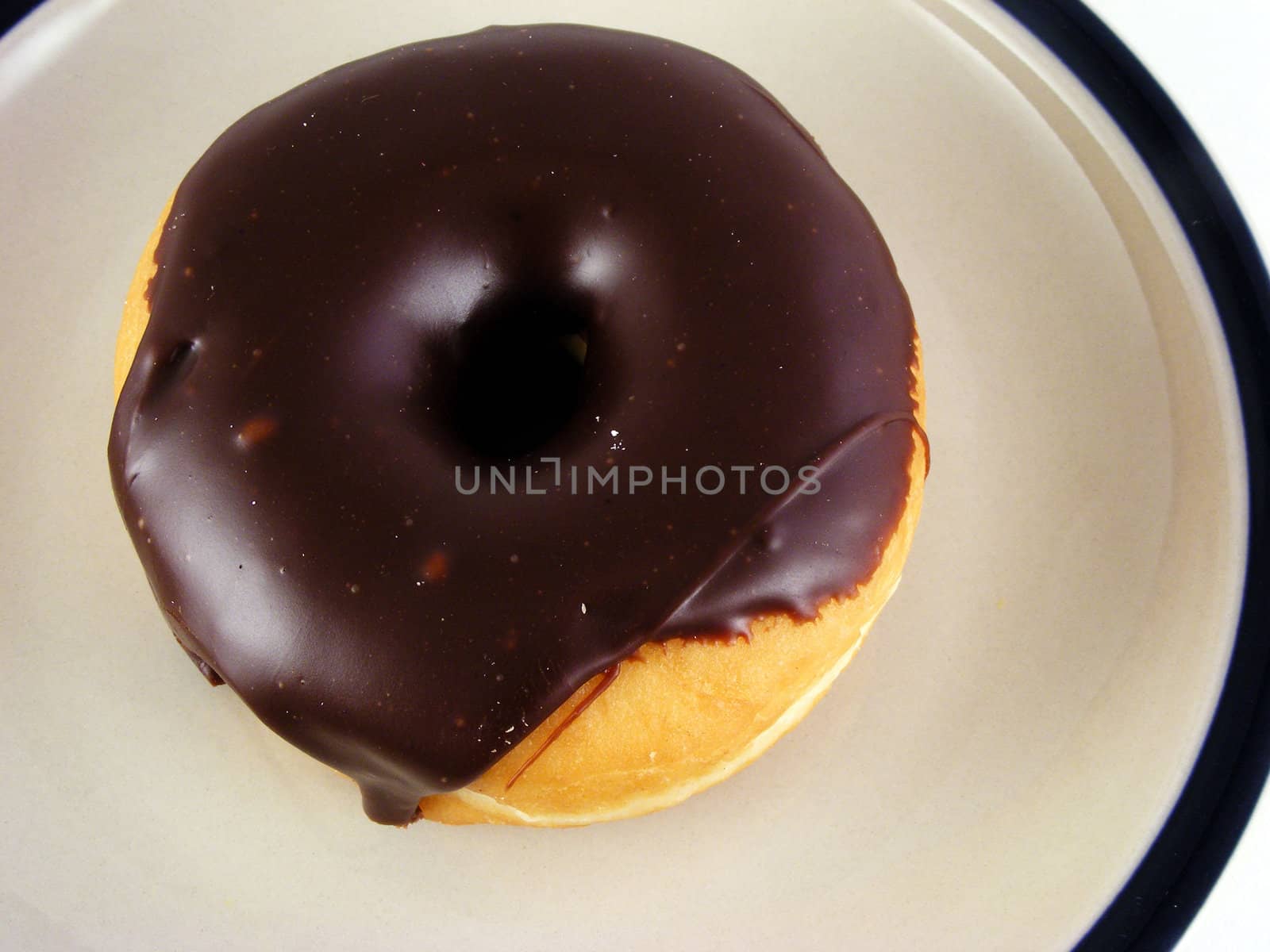 A chocolate iced donut on a plate against a white background.