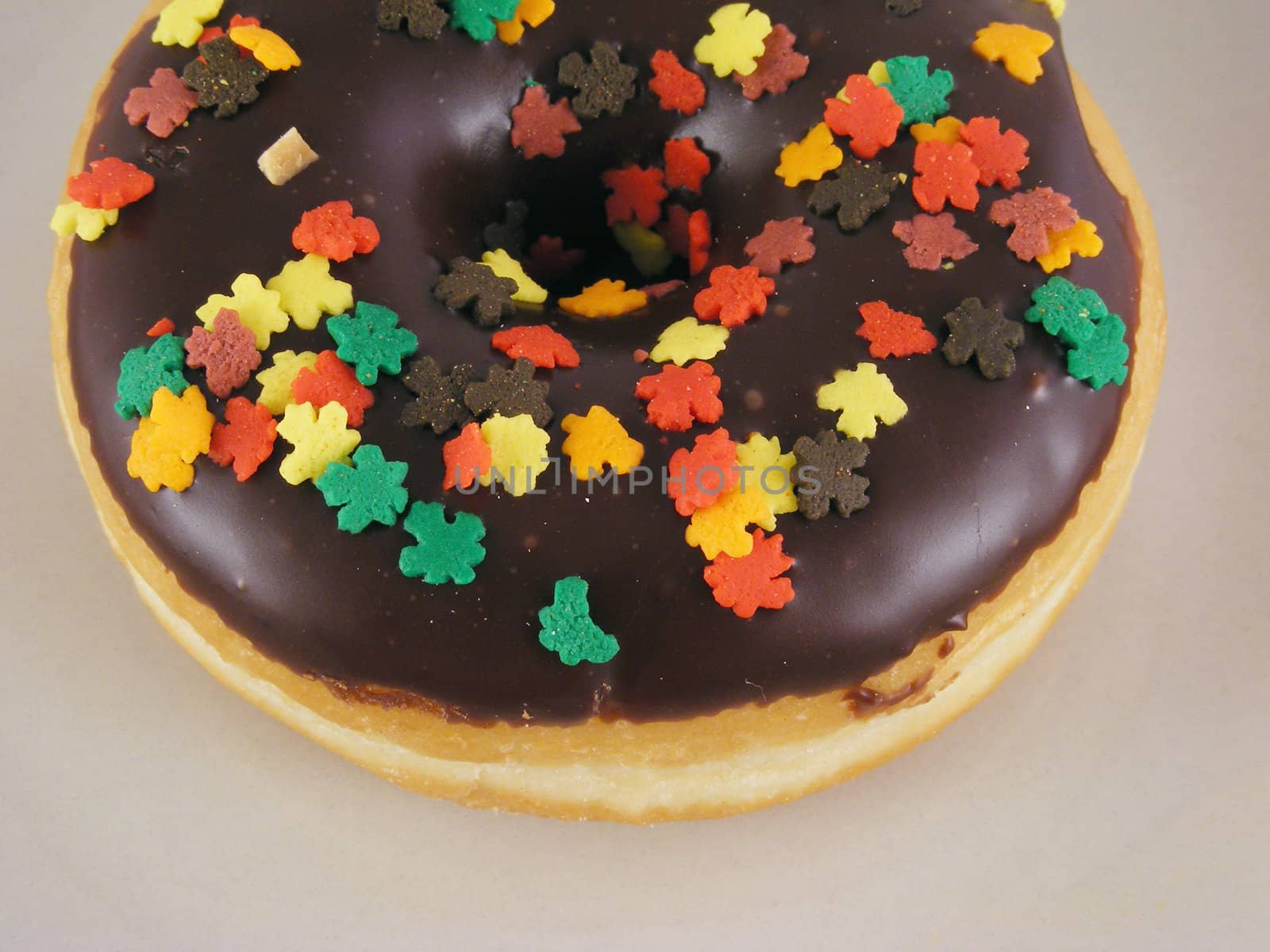 A chocolate iced donut with sprinkles on a plate.