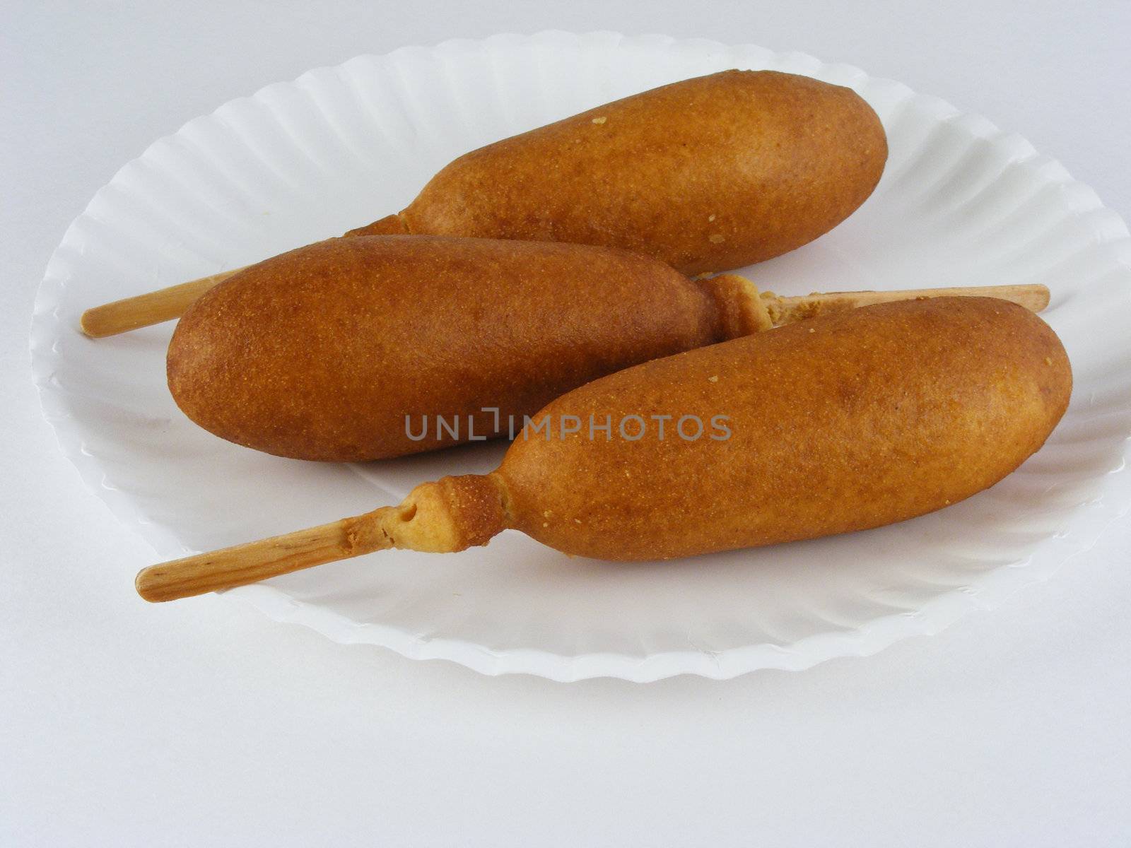 Three corn dogs on a paper plate