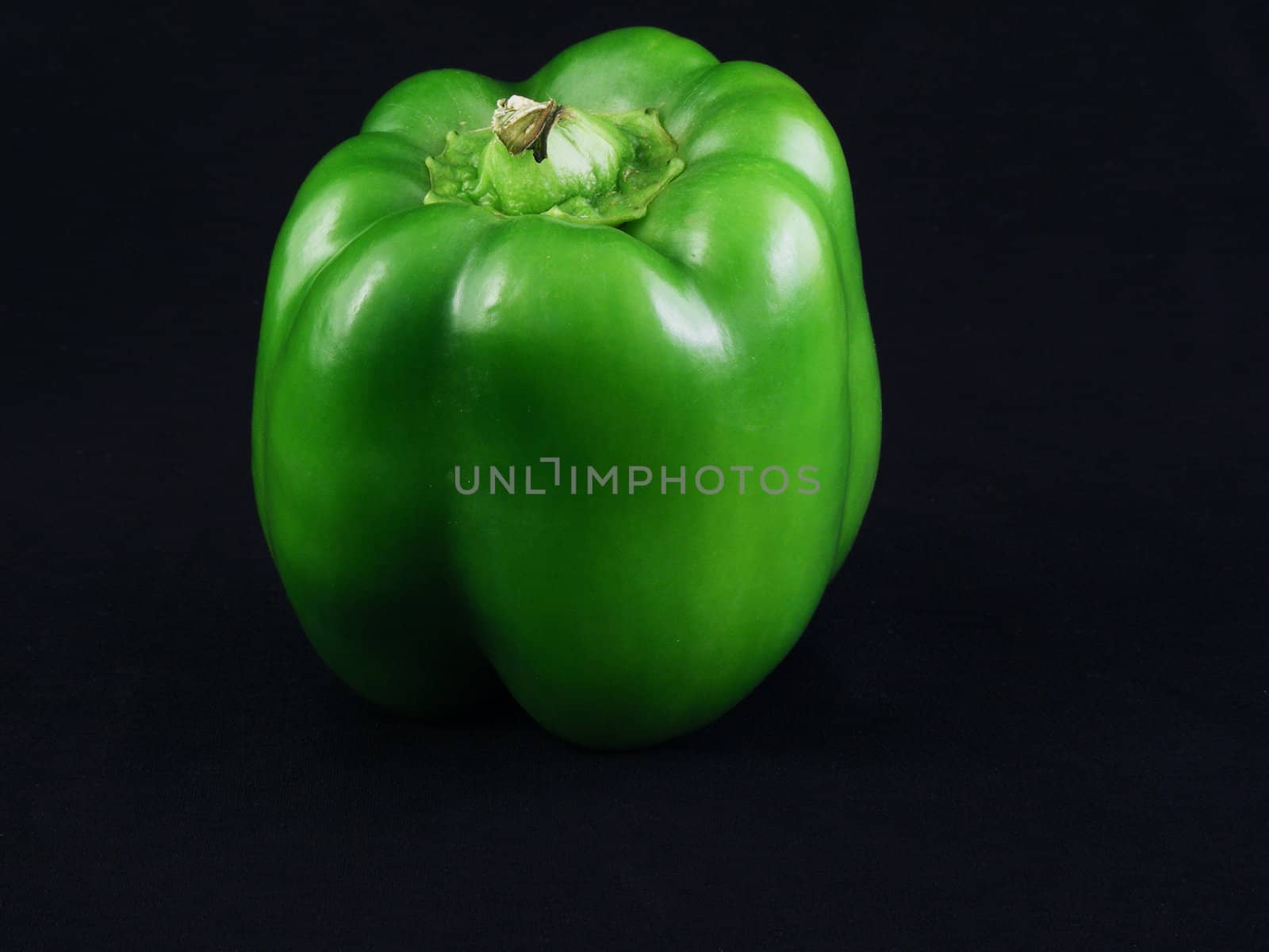 A green bell pepper against a black background.