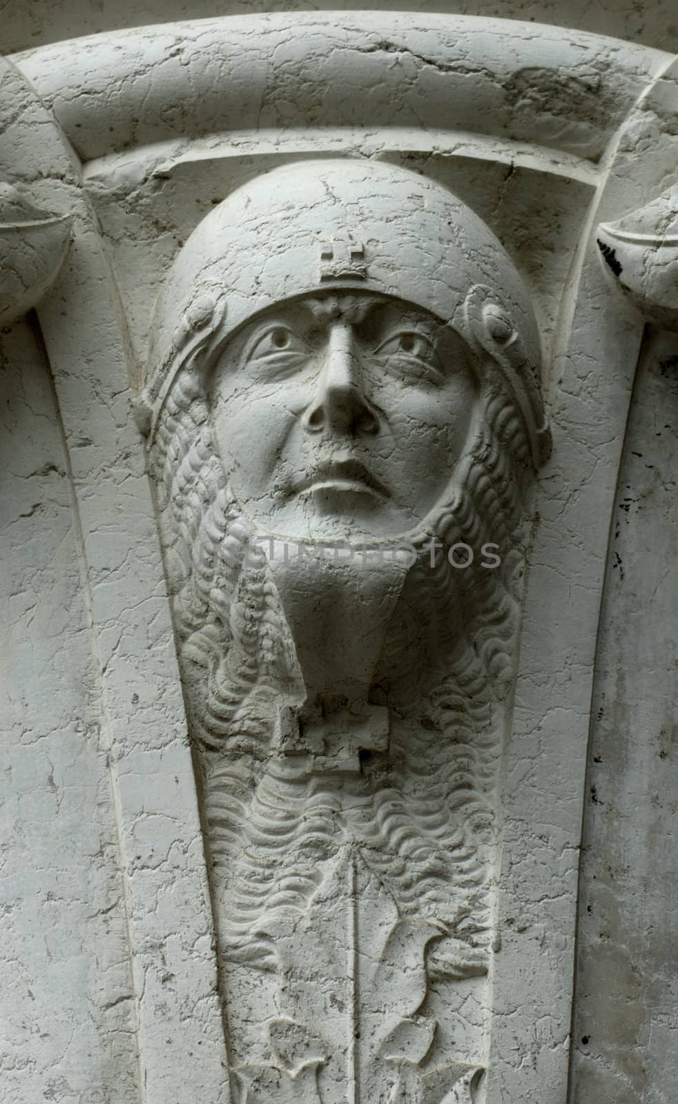 A sculpted soldier's head, protected by a helmet and chain mail, at the top of a pillar on the Doge's Palace in Venice