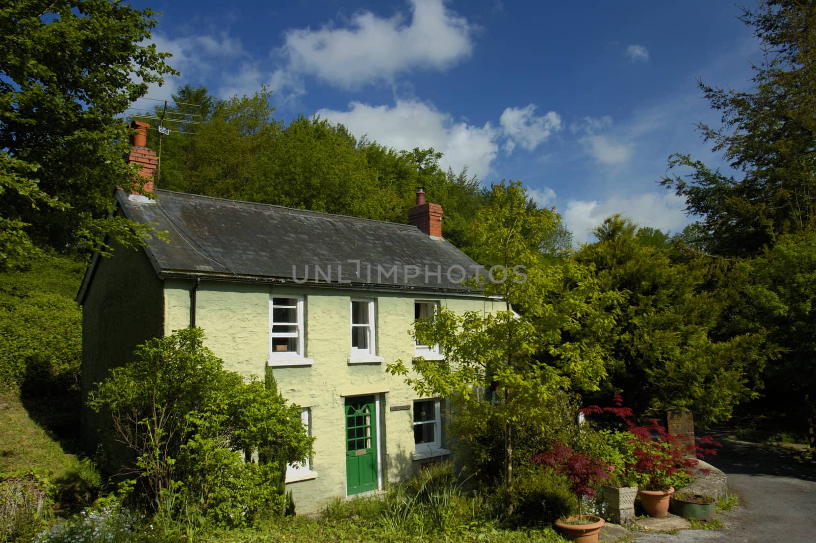 A country cottage, in rural Wales, under a summer sky.
